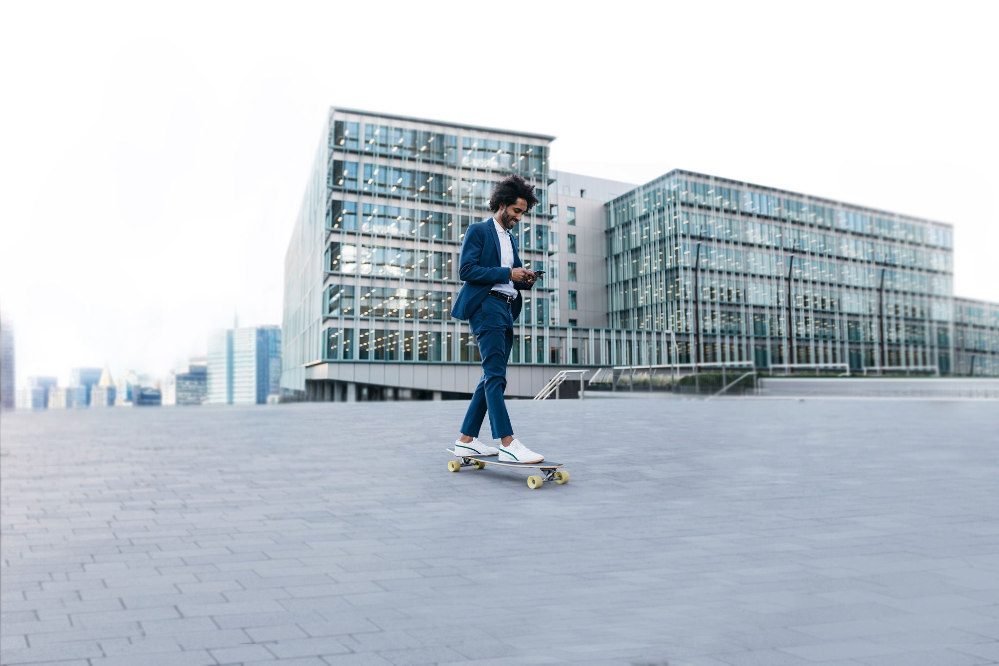Businessman riding skateboard and using cell phone