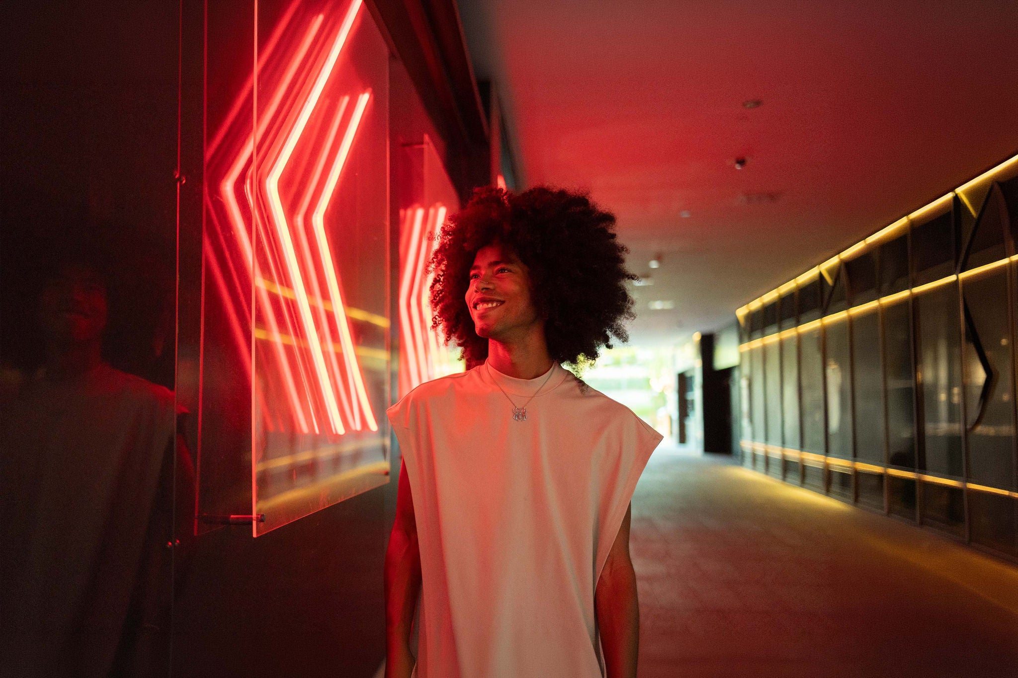 Smiling young man standing near illuminated wall