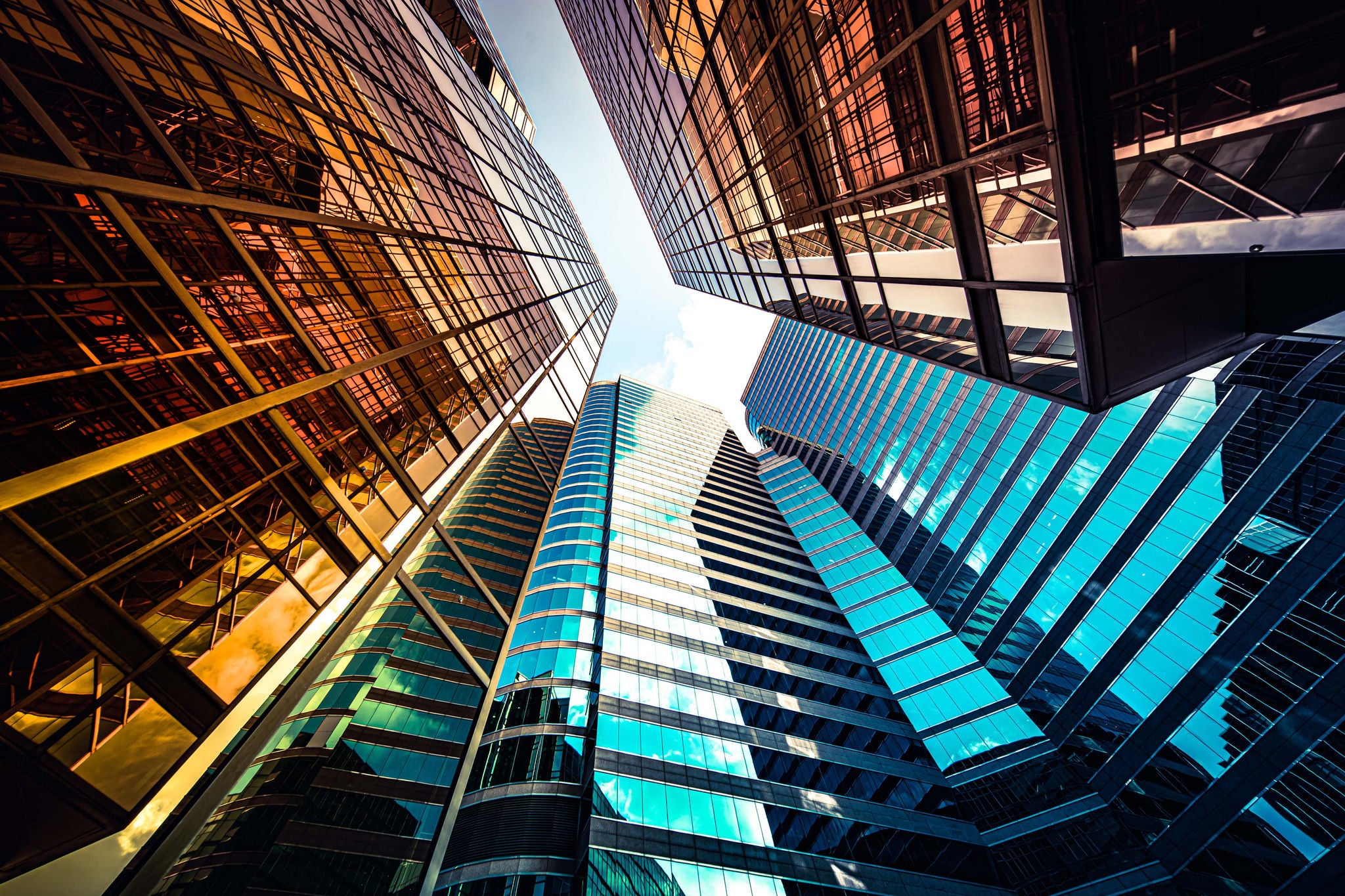 Höga moderna glasbyggnader speglas mot varandra i en färgstark stadsvy