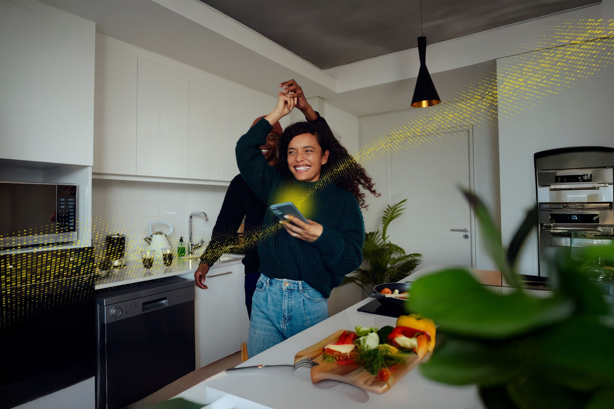 People dancing in a modern kitchen while using a smartphone