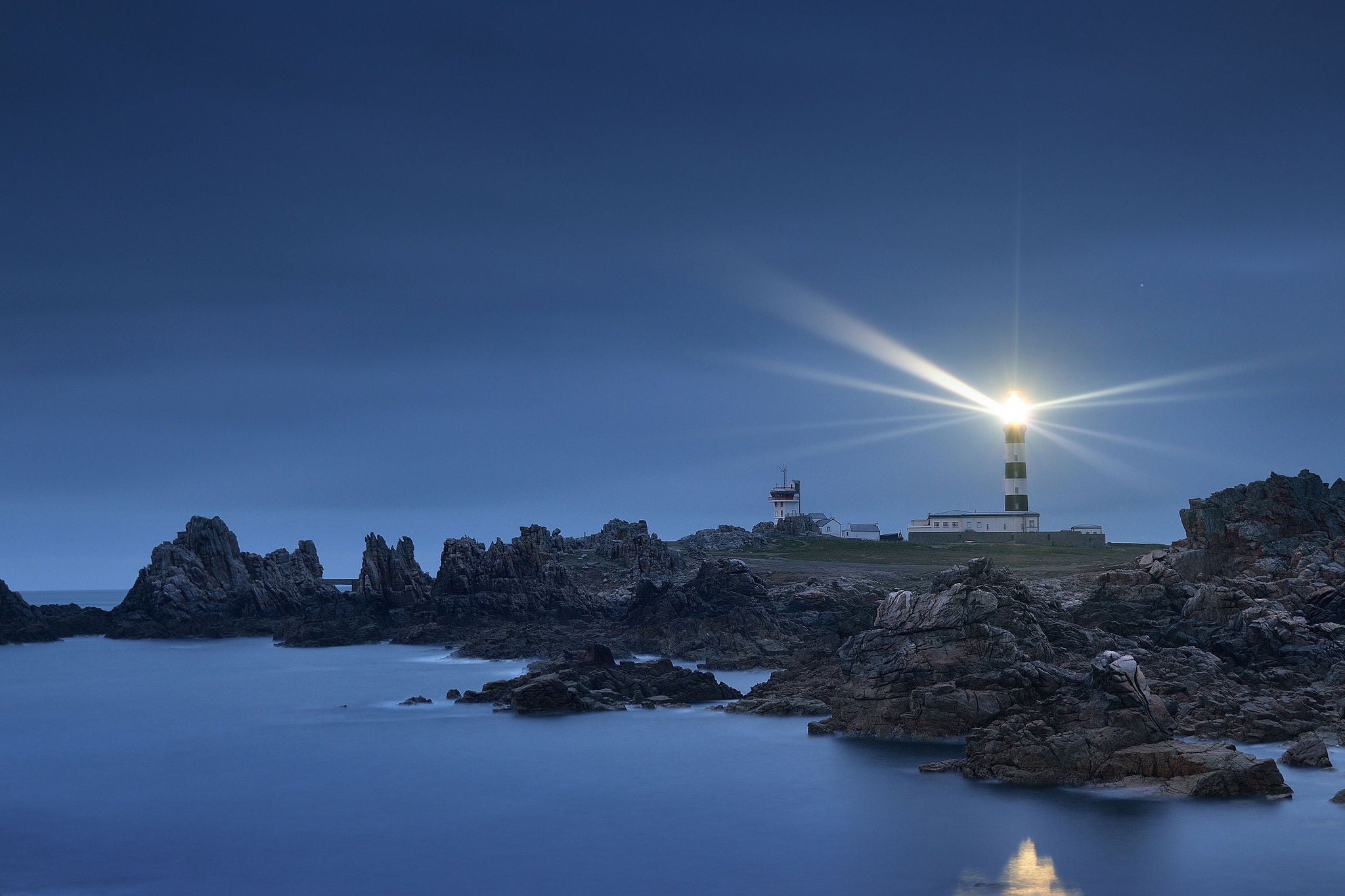 Phare éclairant la côte rocheuse la nuit