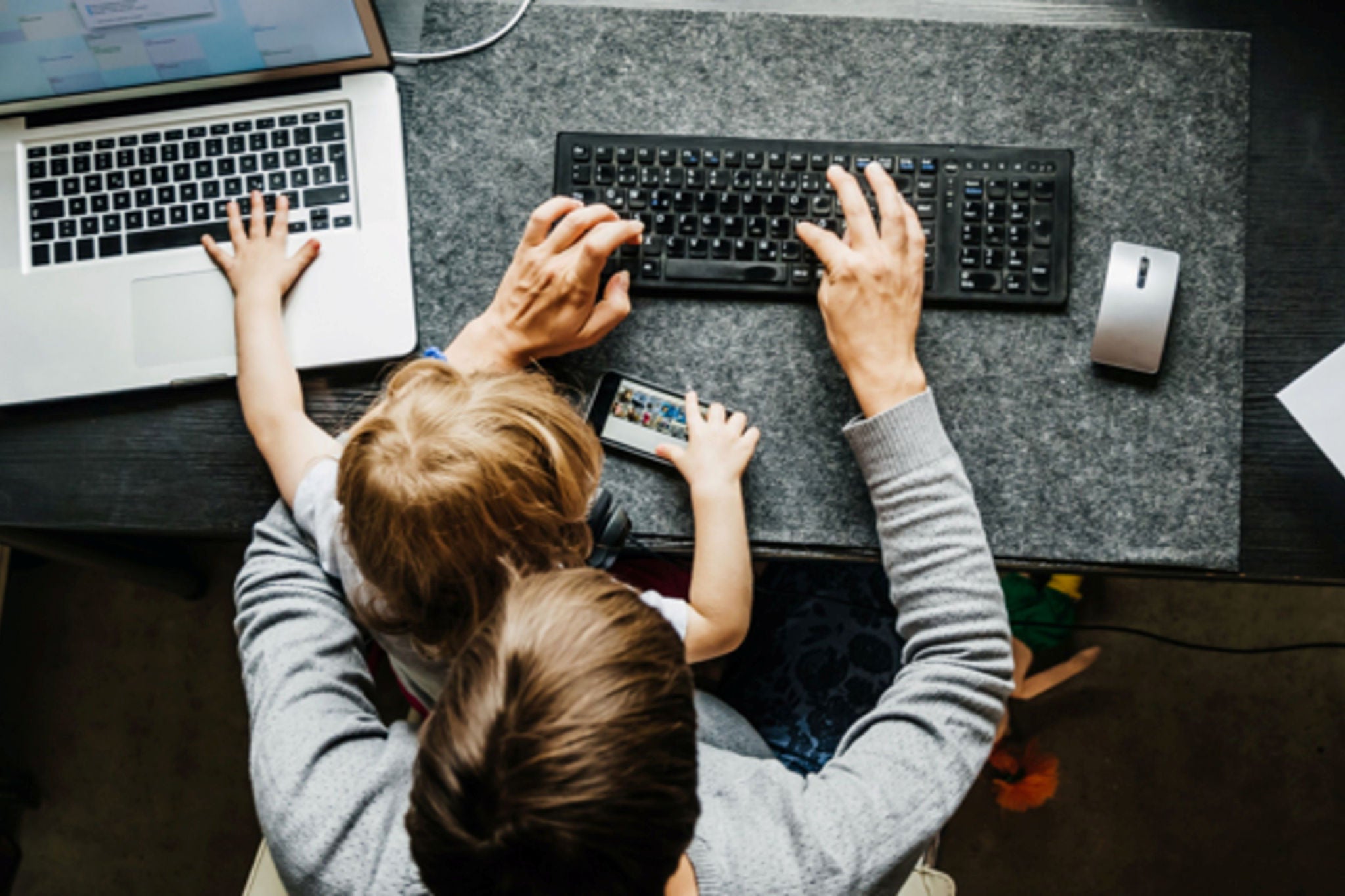 Top down shot of parent using a laptop with baby