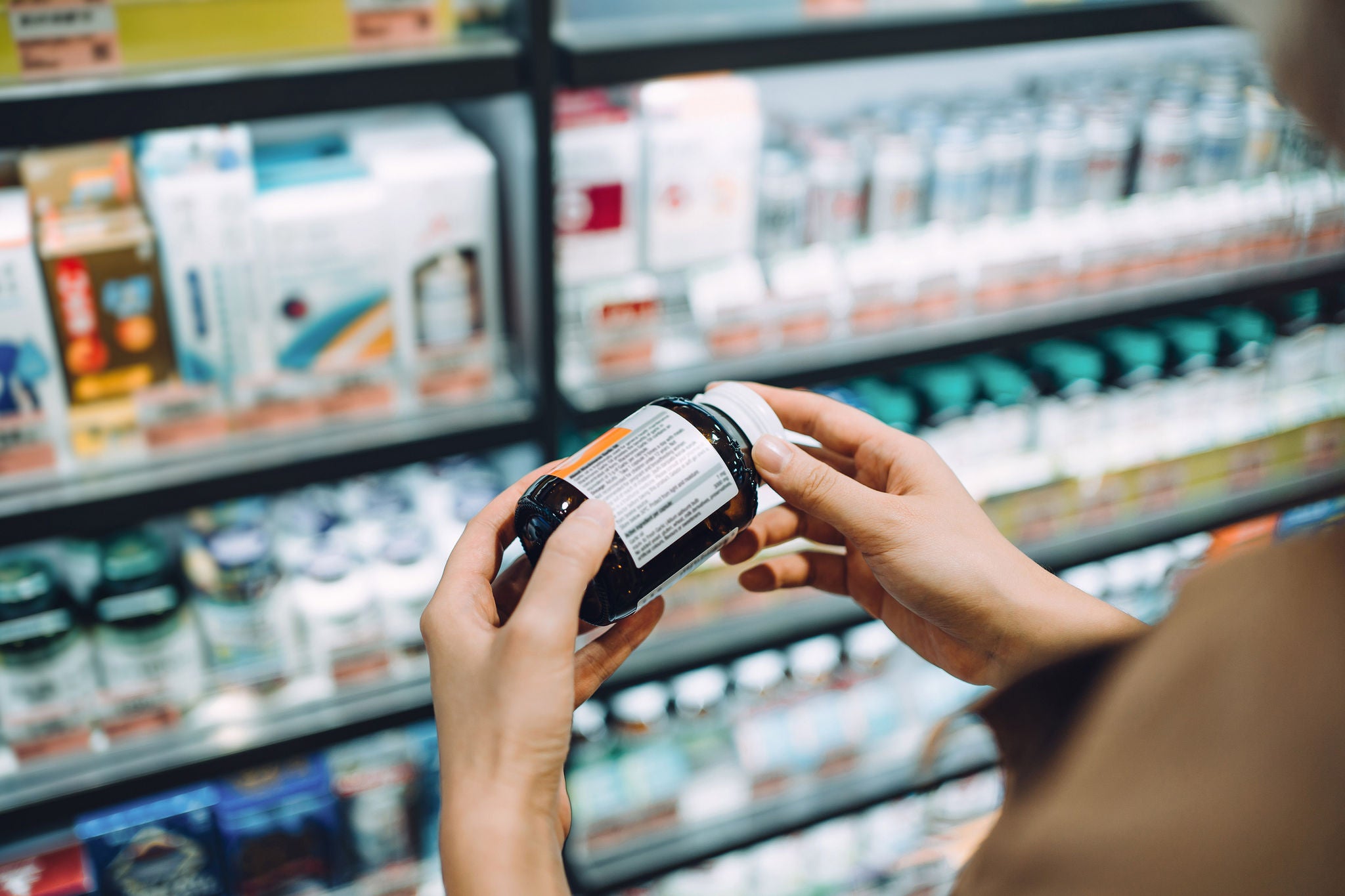 Close-up of a customer examining product information in a retail health aisle.