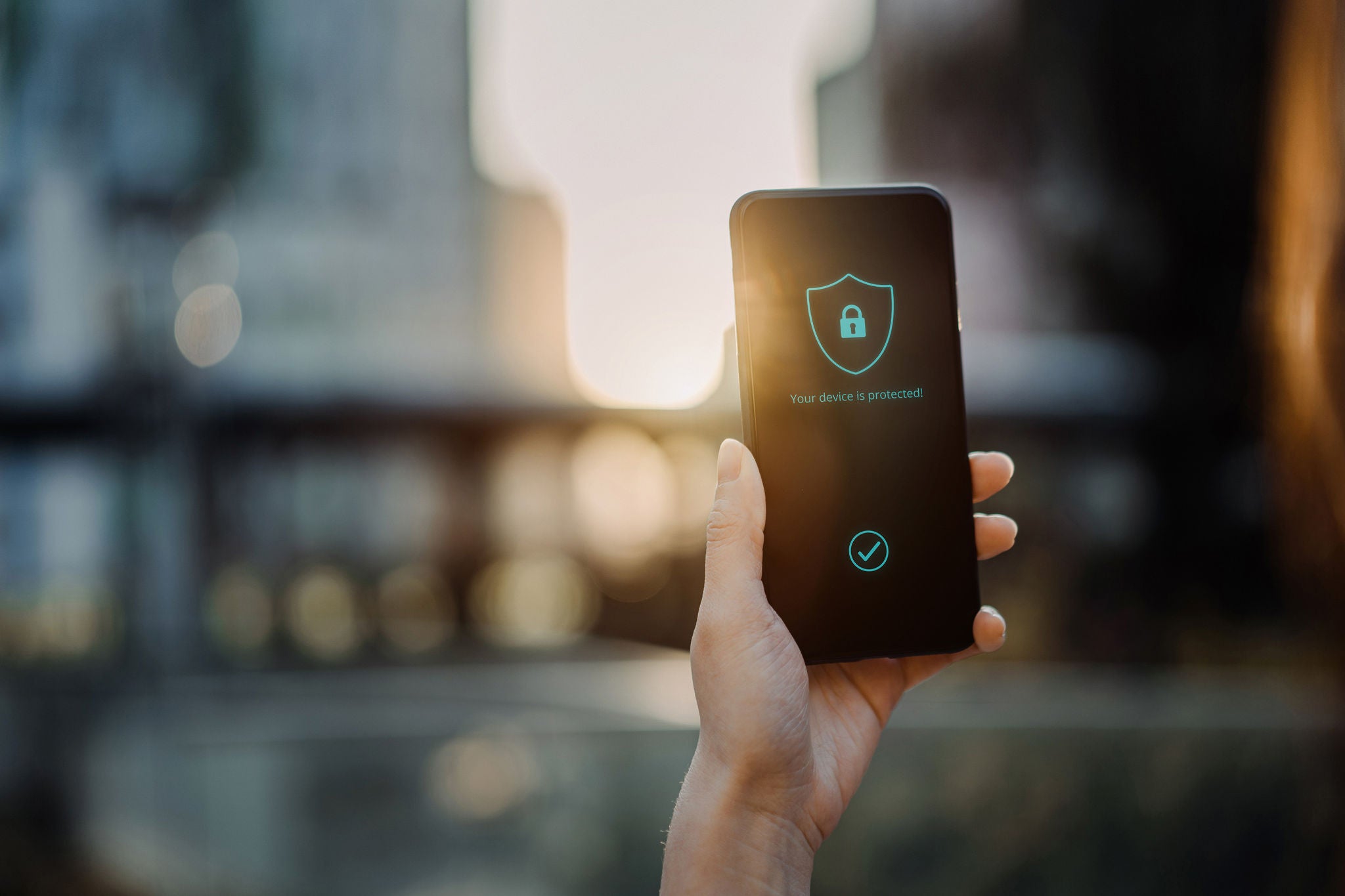 Close up of young woman using smartphone in downtown district in the city against urban city scene, with a security key lock icon on the smartphone screen.