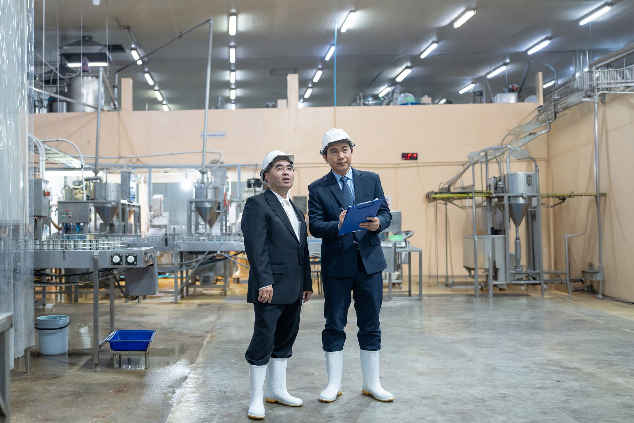 Businessman owner and partner discuss operations while inspecting food production line in canned fish factory