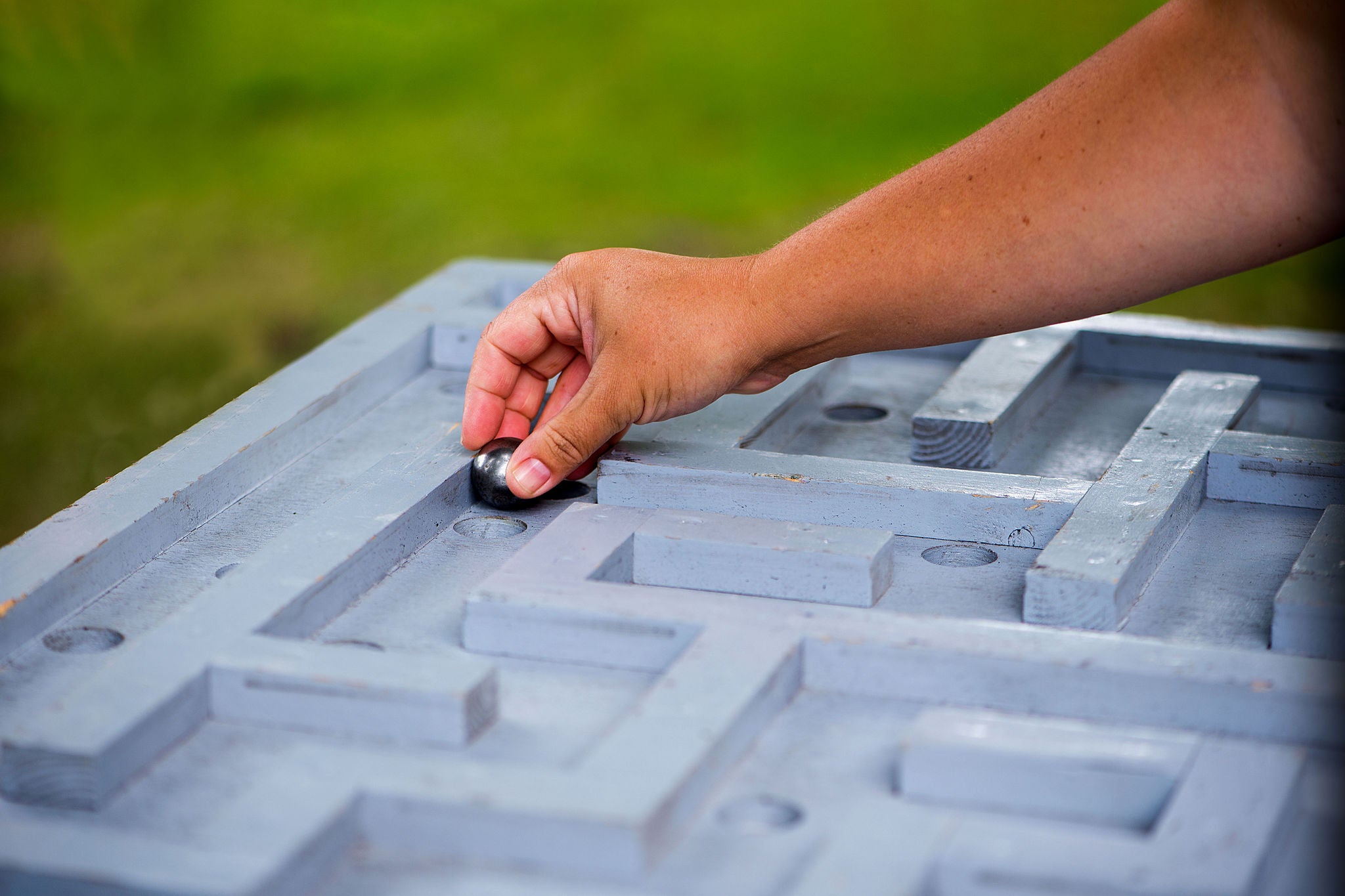 Close up of hand placing marble into wooden maze game