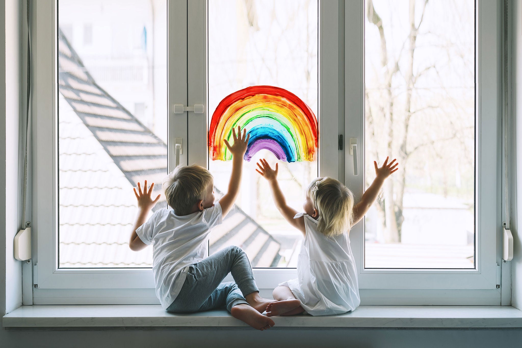 Little children on background of painting rainbow on window