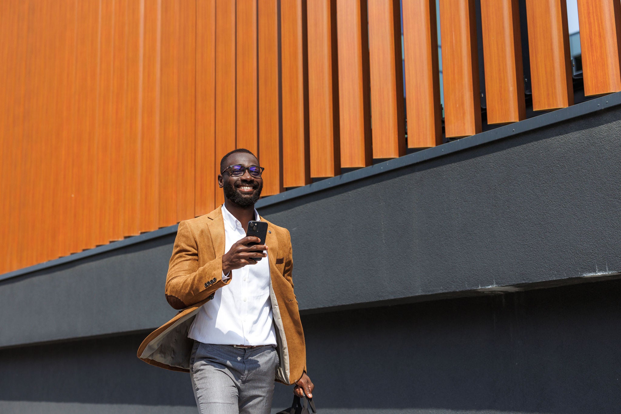 Mid adult African American stylish businessman walking and using phone