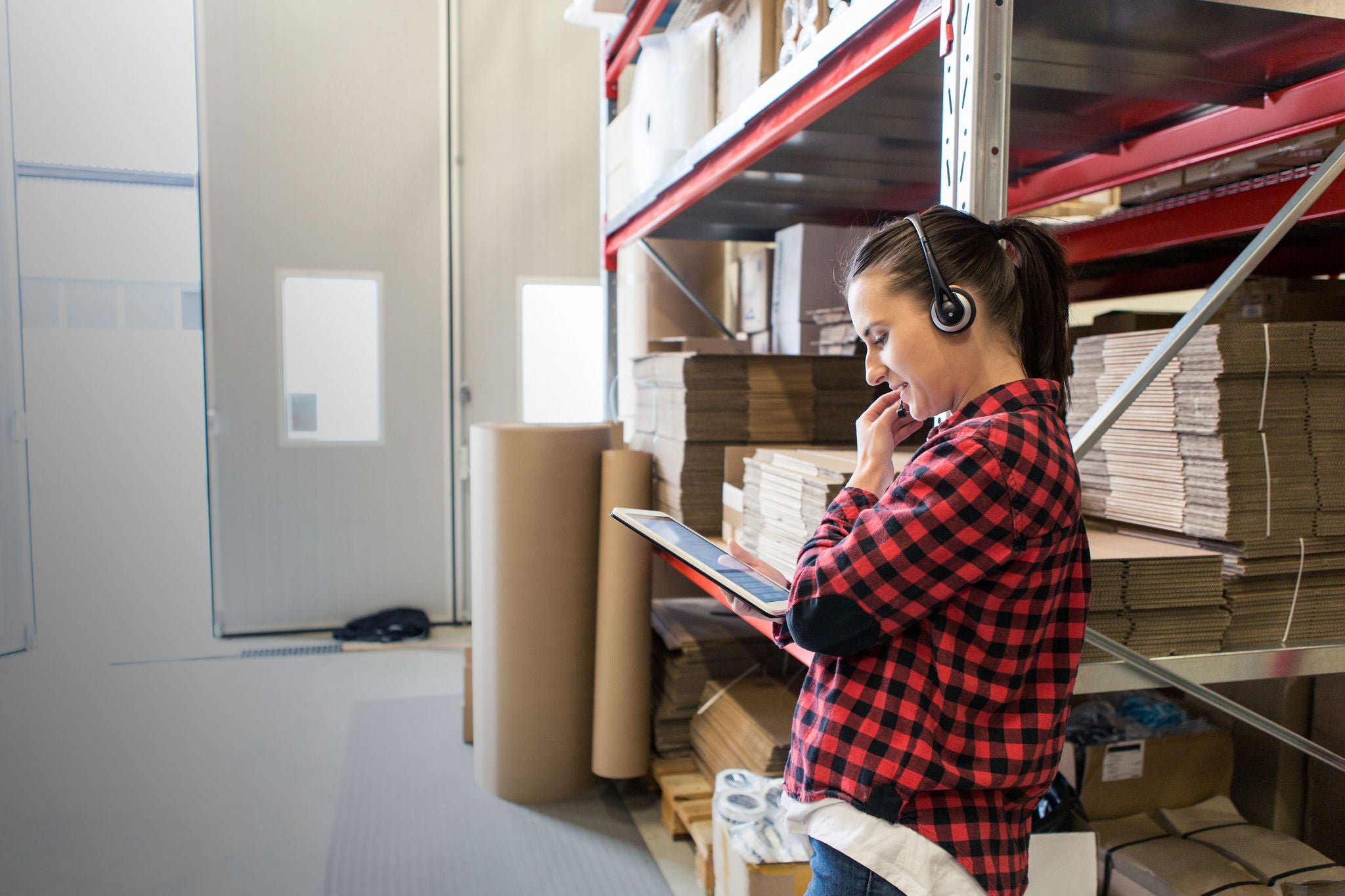 woman with headset and tablet in warehouse