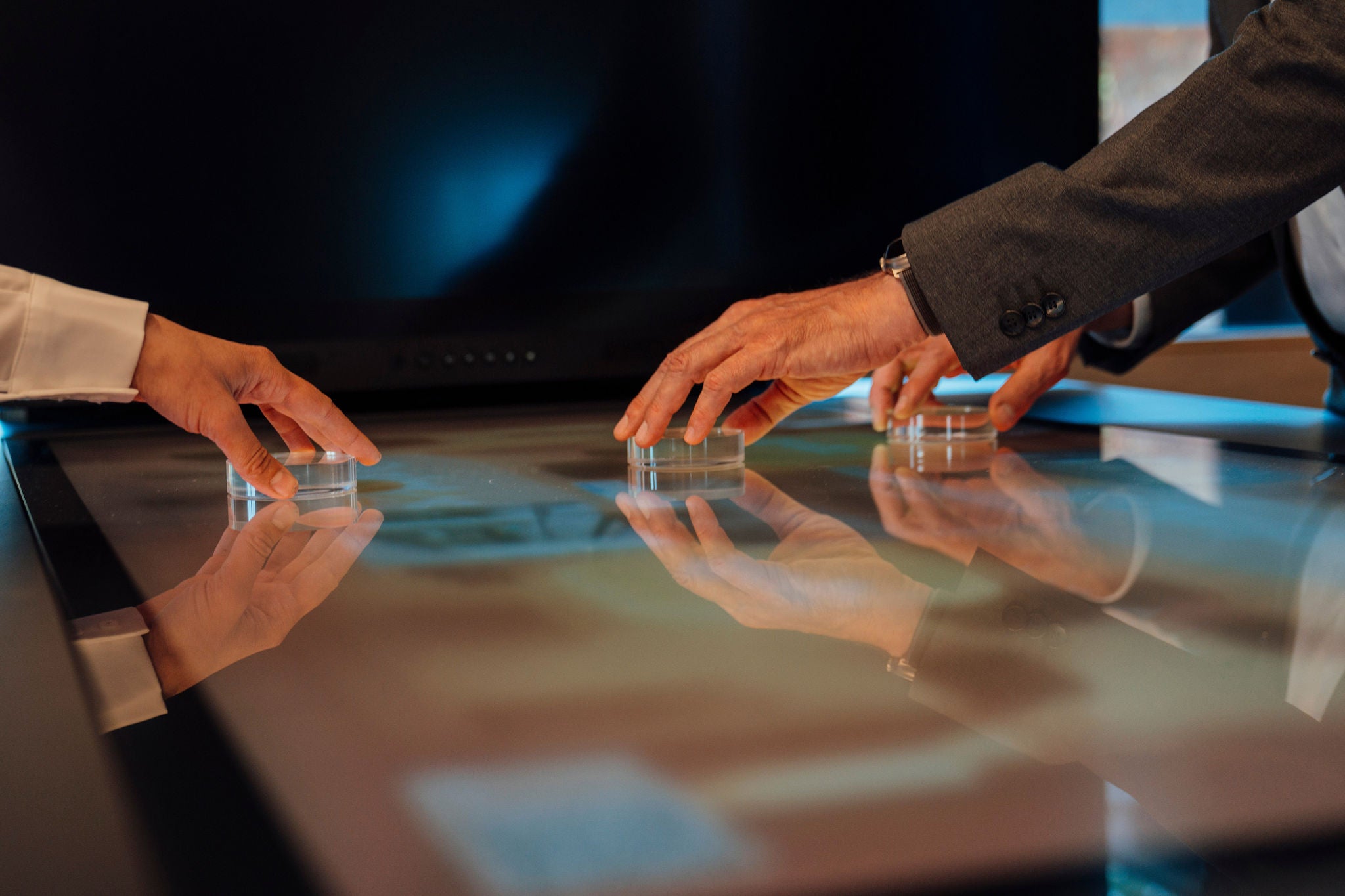 Hands collaborating on futuristic touchscreen technology in modern office