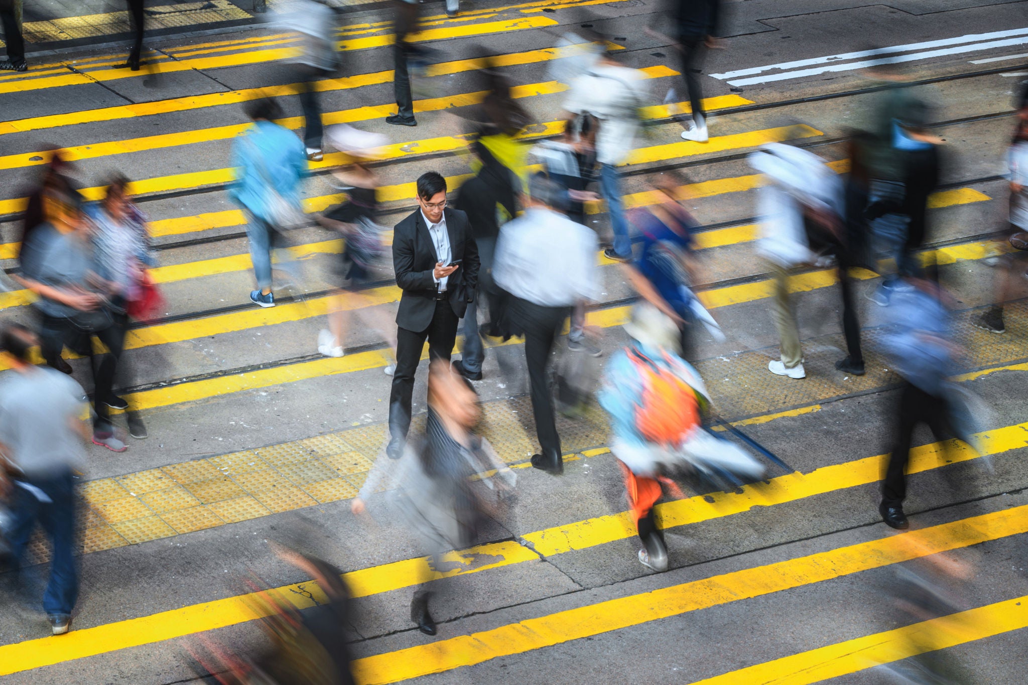 A crowd of unrecognizable blurred business people on their way from work, crossing the street.
