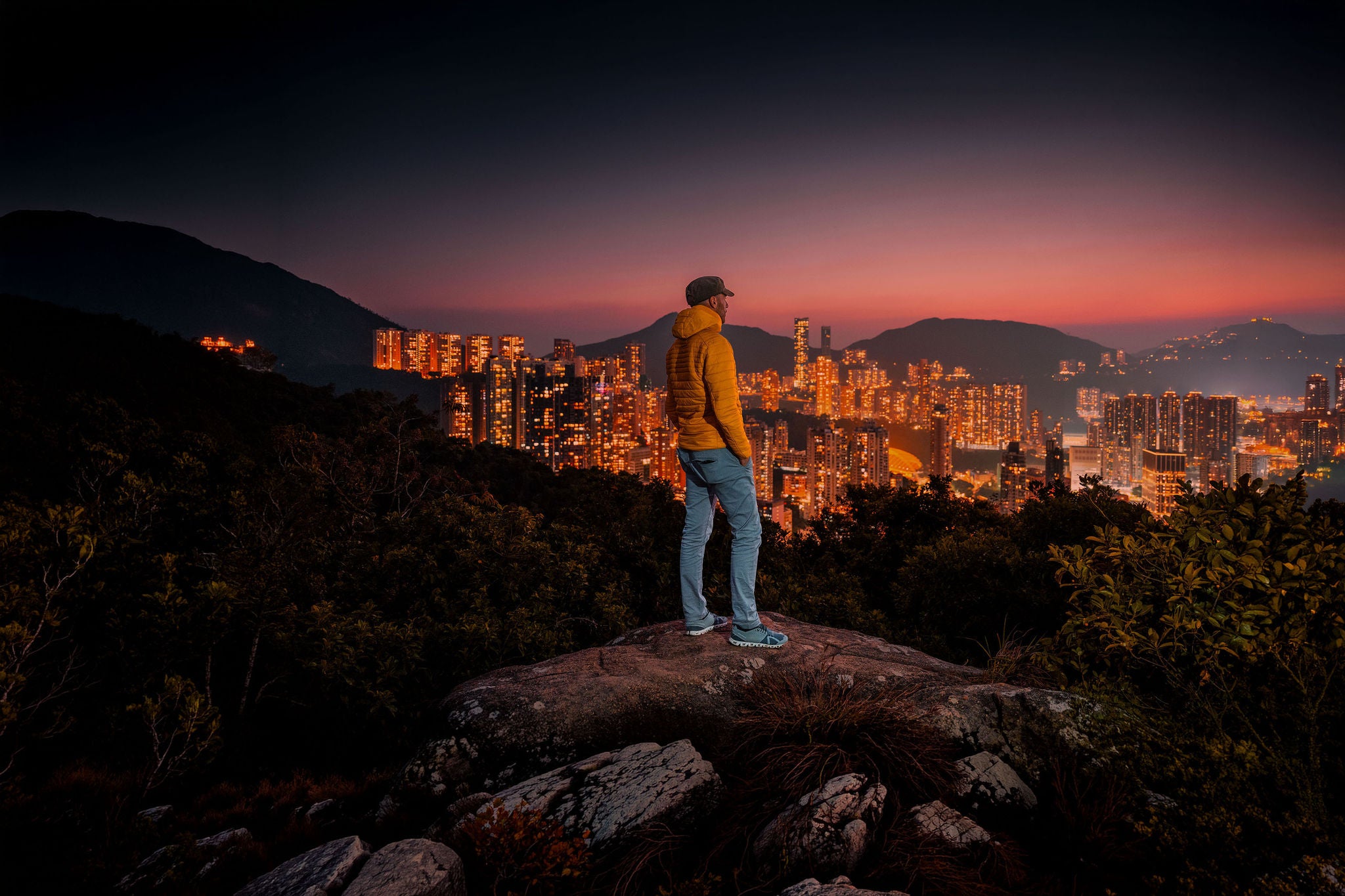  man in yellow jacked looking over city at night