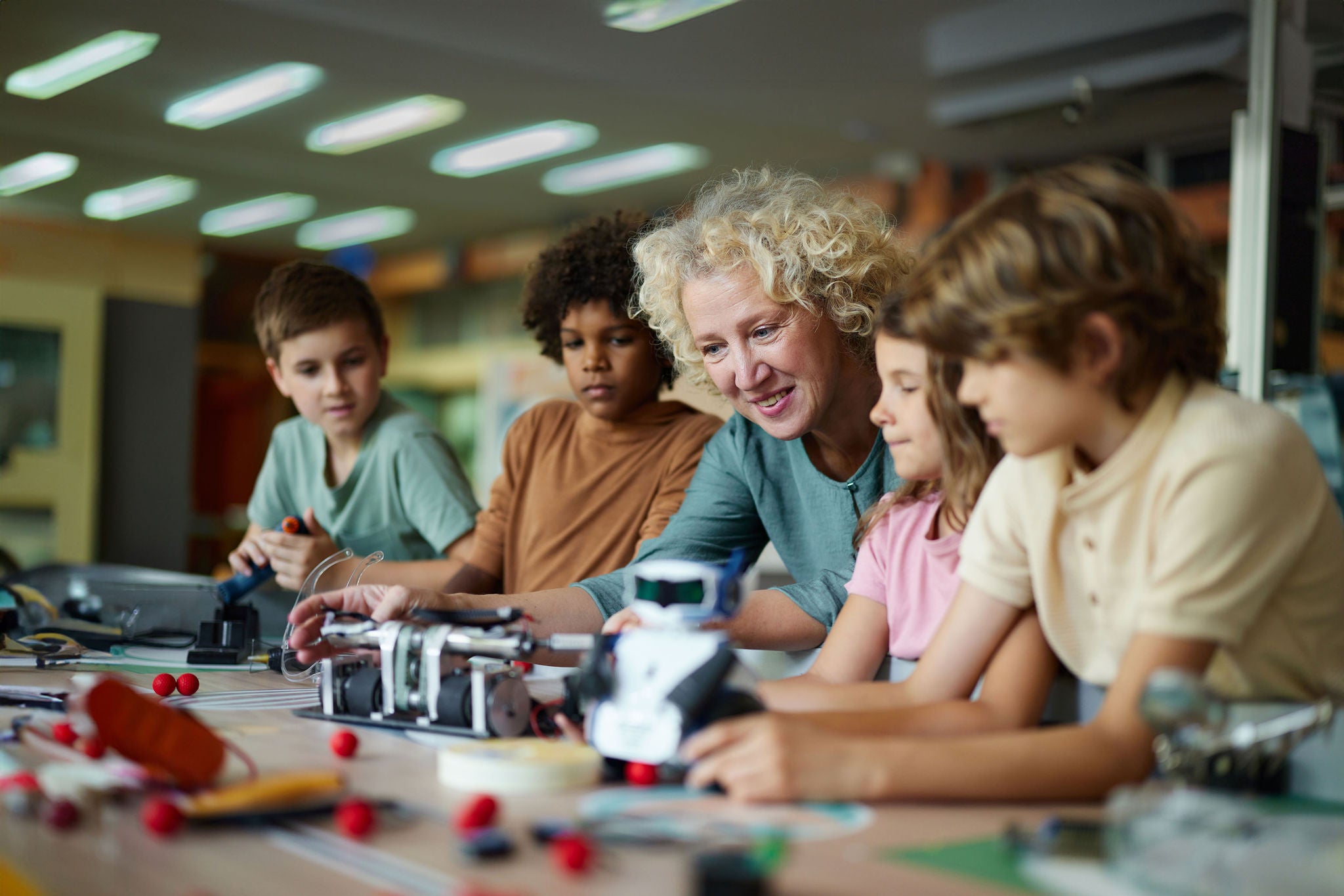 Happy female teacher assisting little scientists in making a futuristic robot in laboratory.