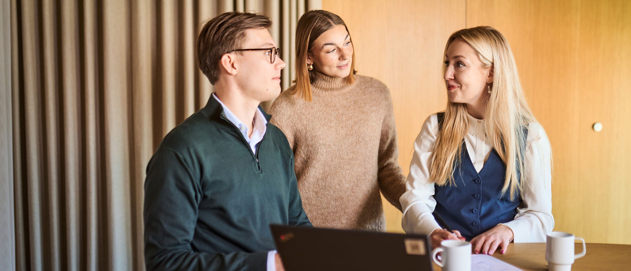 Team discussing ideas together around laptop in modern office setting