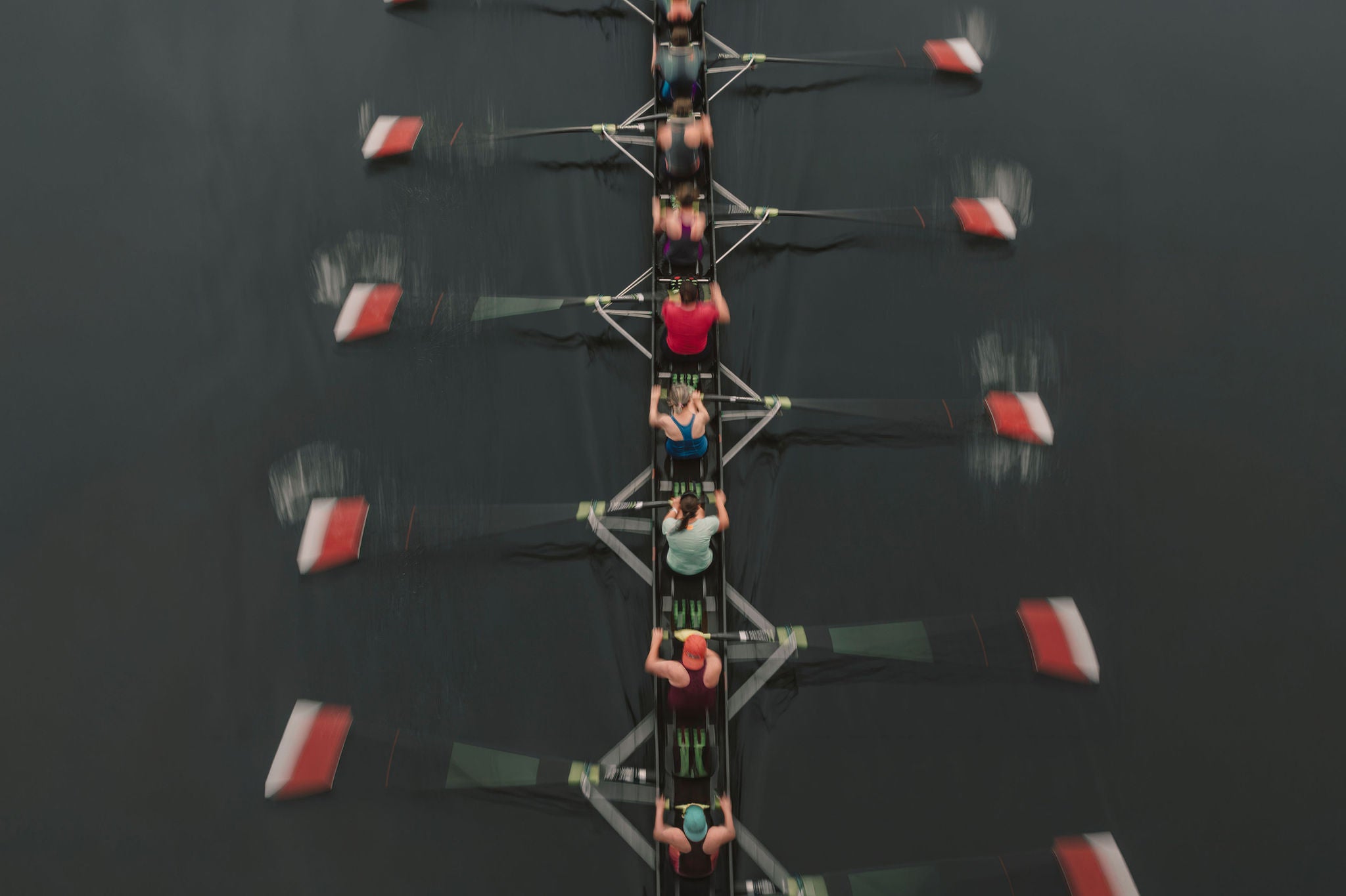 Eight-person rowing team moves in sync across calm water