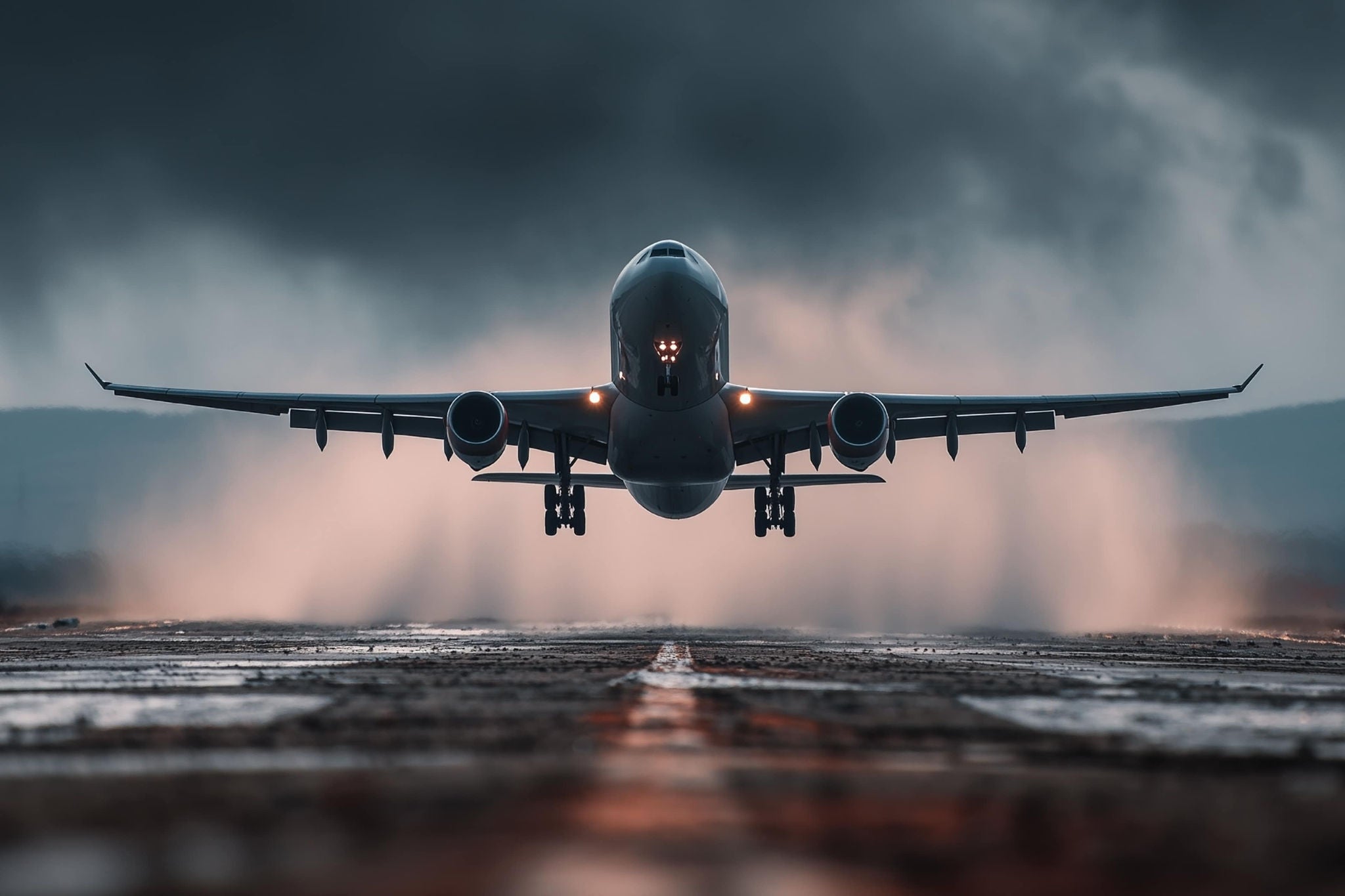 A smiling young woman with headphones and folders, standing outdoors on a college campus.