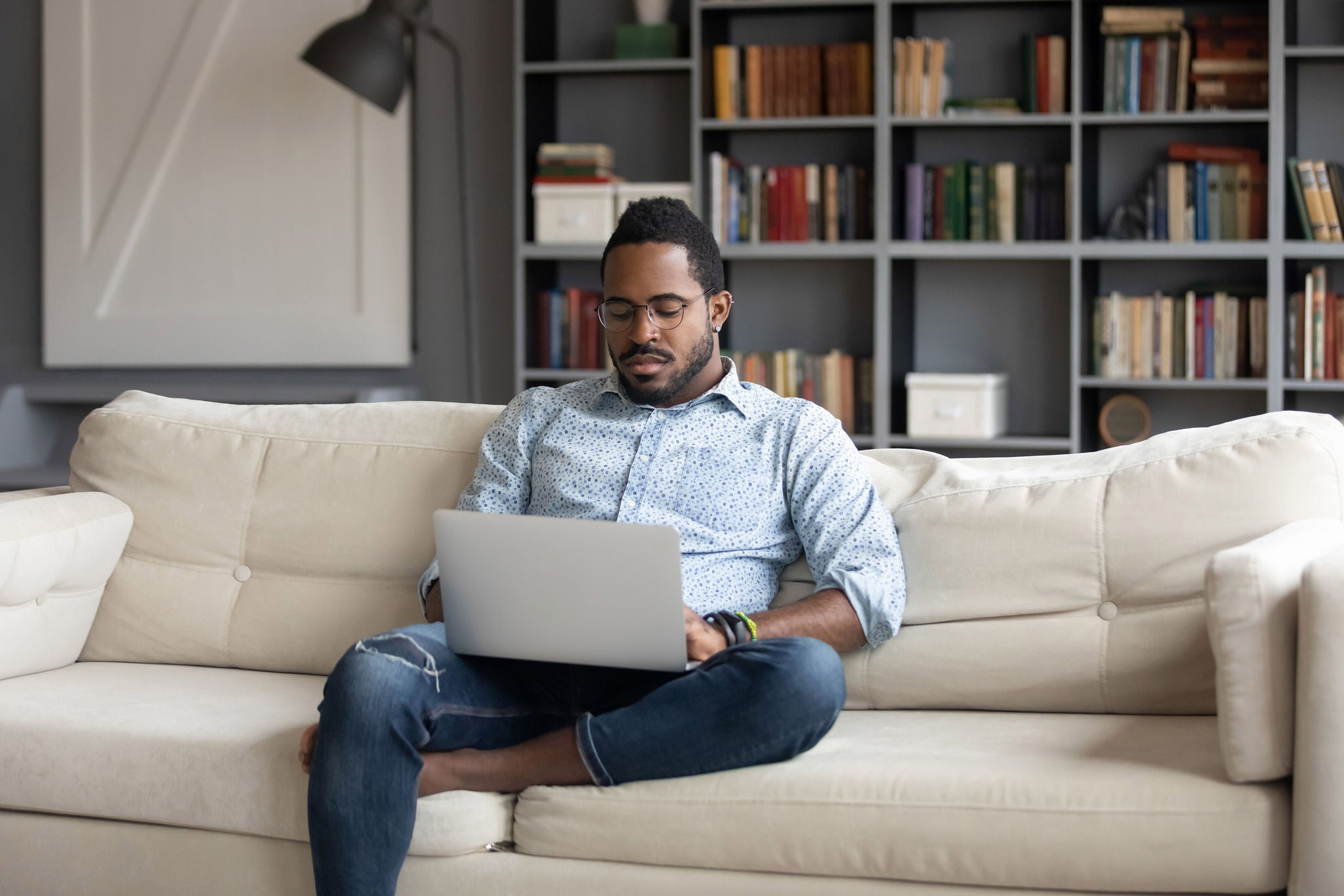 Focused young African American businessman working remotely on sofa