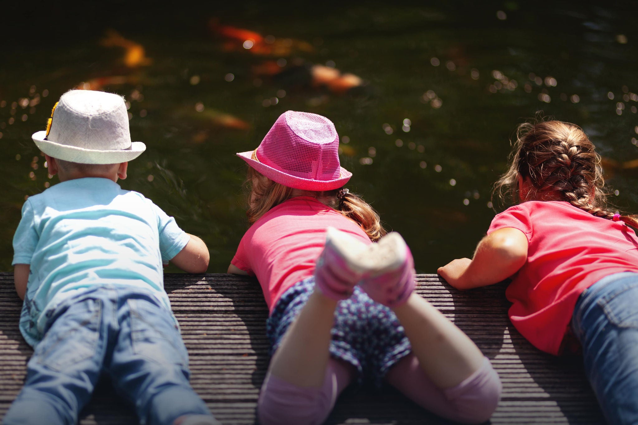 A smiling young woman with headphones and folders, standing outdoors on a college campus.