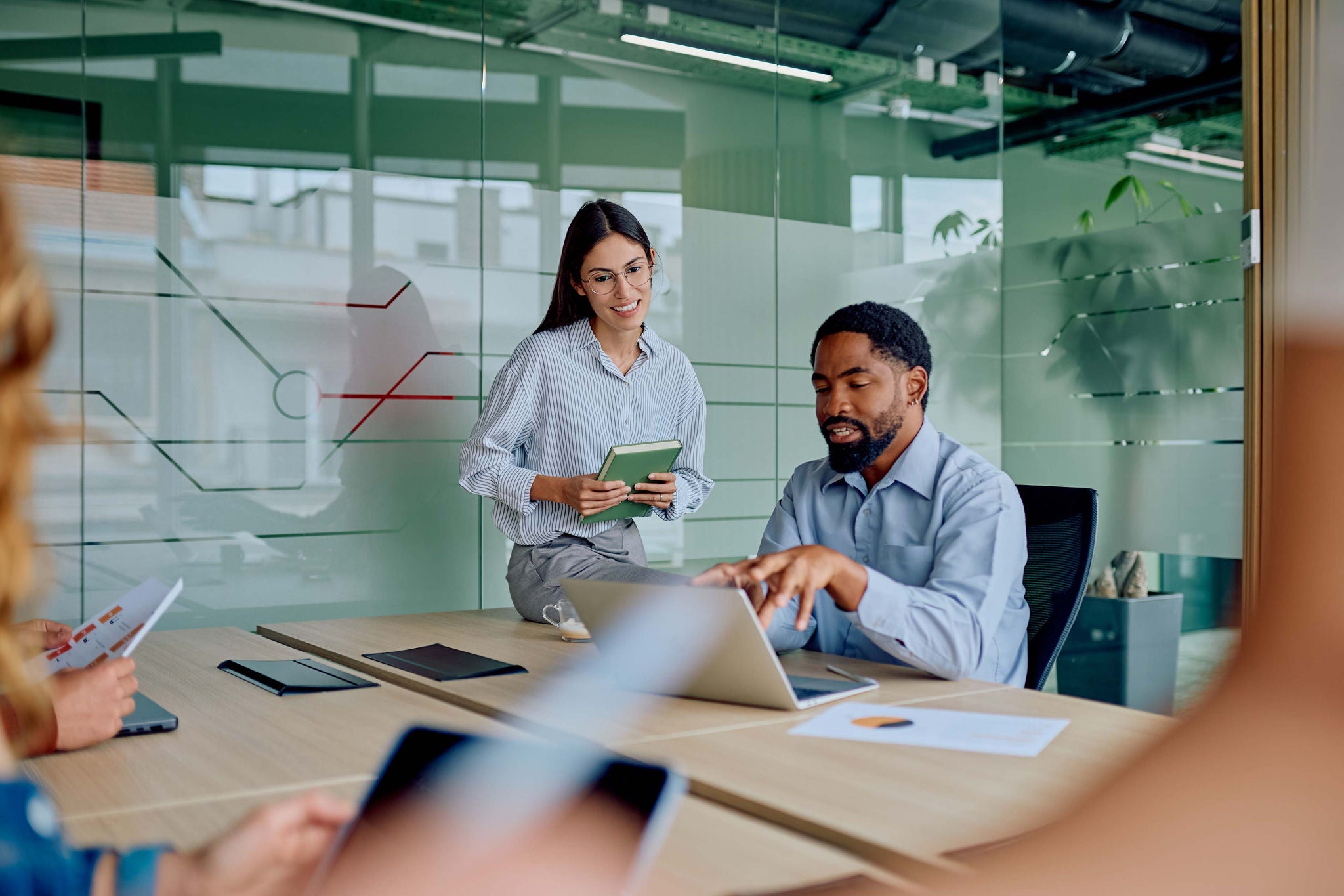 Personen arbeiten gemeinsam an einem Konferenztisch mit Laptops und Dokumenten