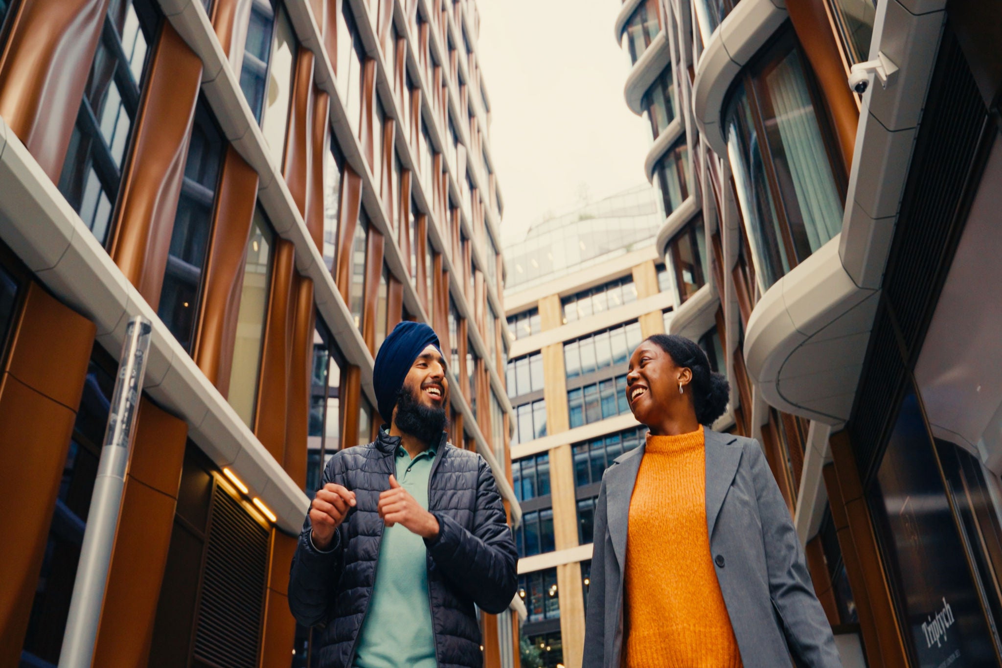 Two colleagues walking together between modern office buildings