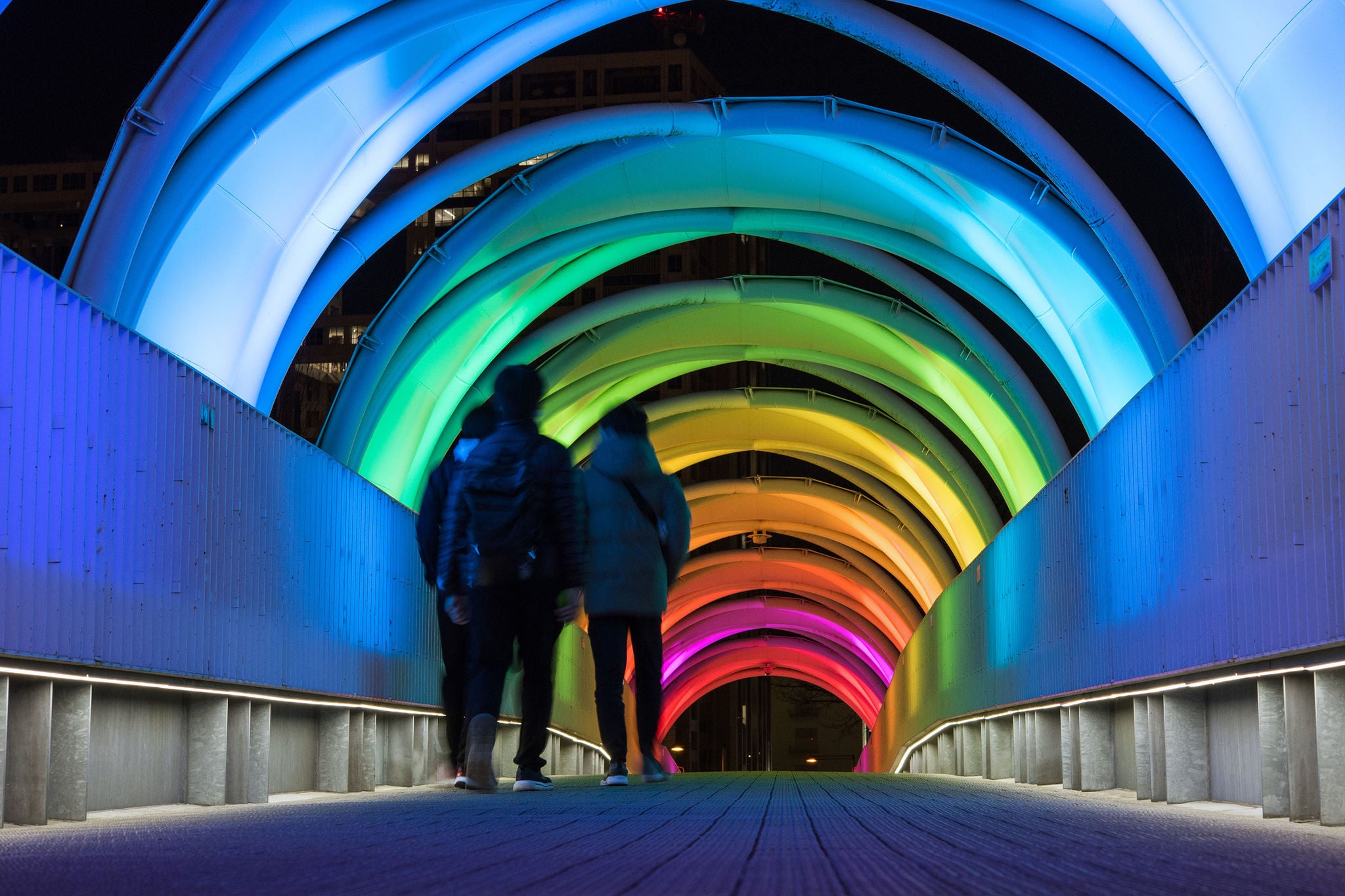 People walking through illuminated colorful tunnel at night in Odaiba, Tokyo