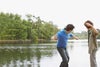 Father and son skimming stones in lake