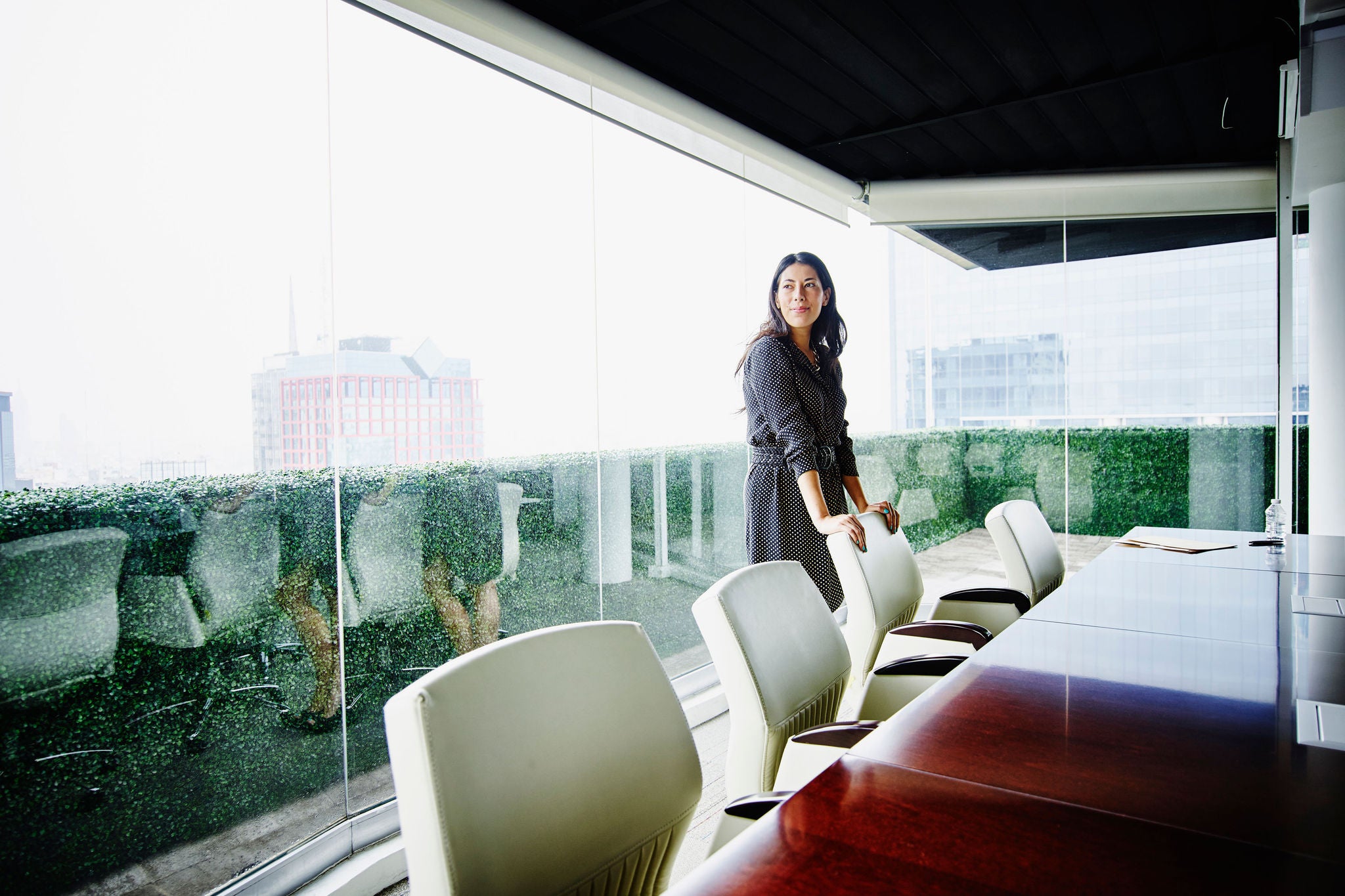 Femme debout dans une salle de réunion lumineuse avec vue sur la ville