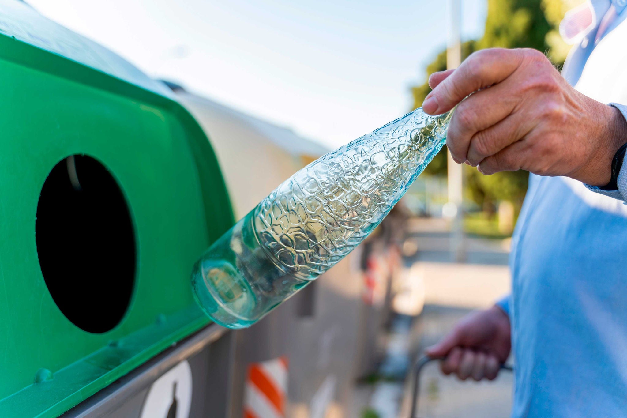 Close-up of man putting bottle into bottle bank