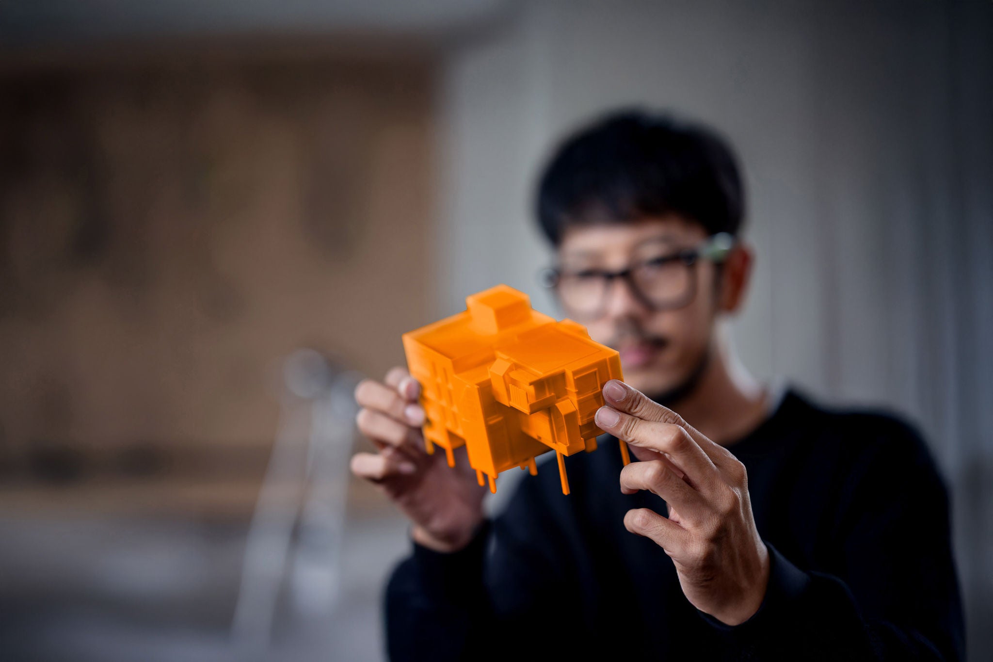 A construction designer reviews an architectural model prototype printed by a 3d printer machine at an architect's office.