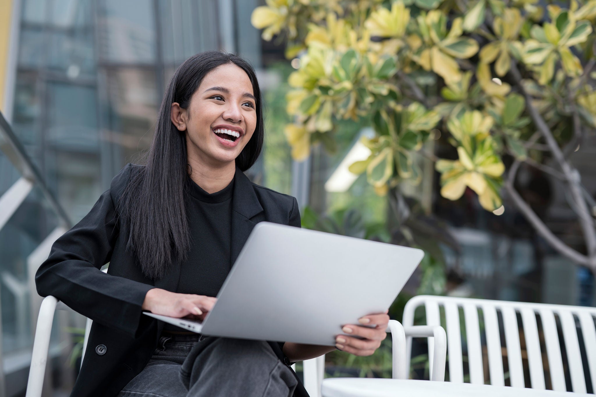 Young professional working on a laptop outdoors near an office building