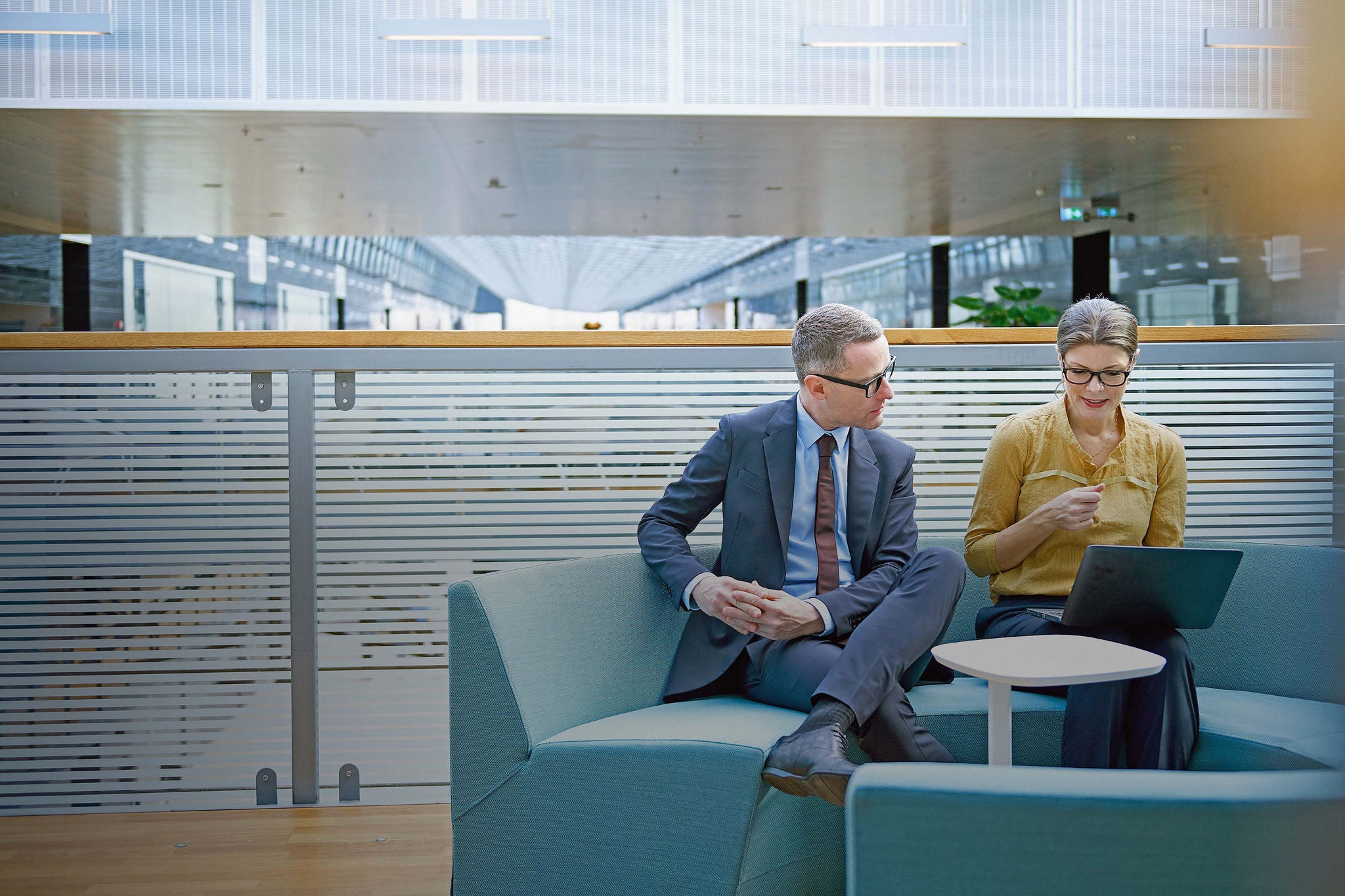 Businessman and woman looking at laptop in office atrium