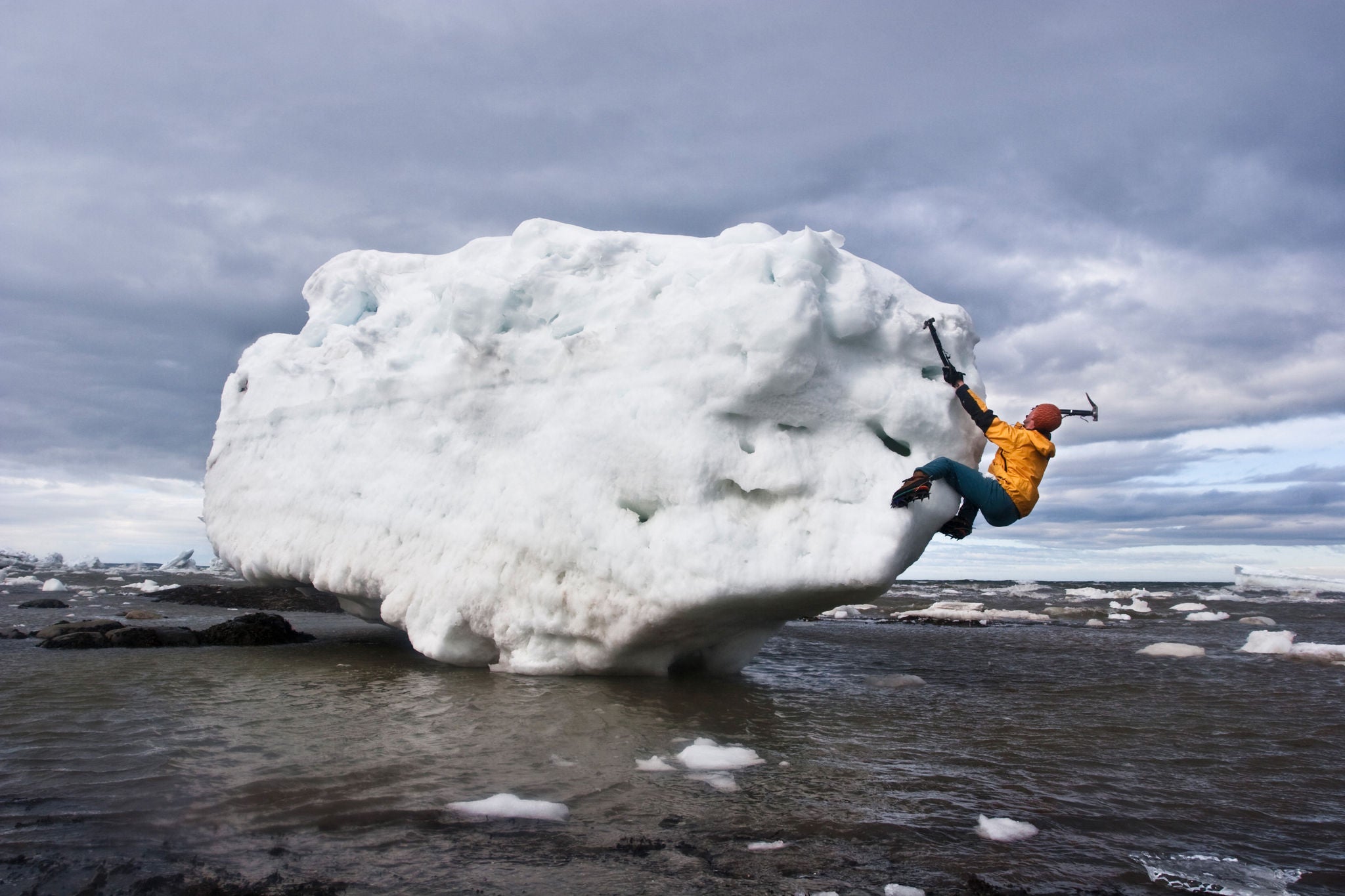 Climber scaling a large floating iceberg