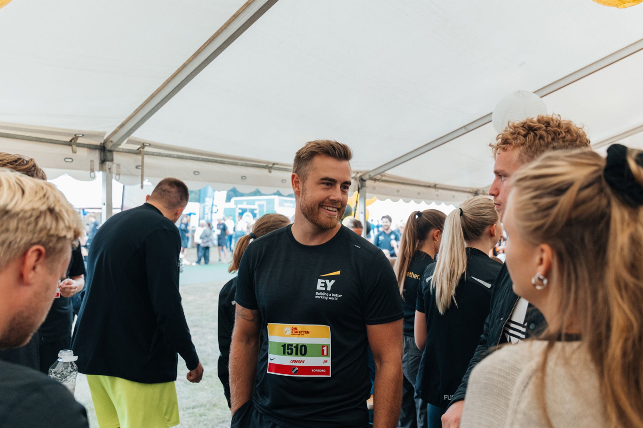 Employees interacting at corporate outdoor event under EY tent