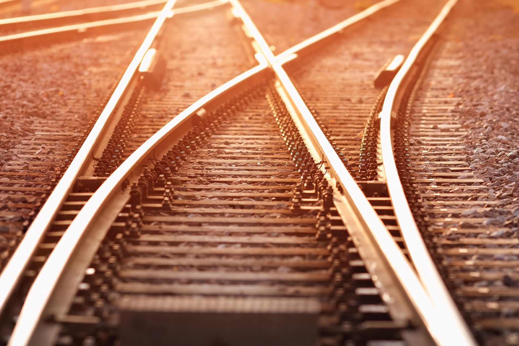 Verzweigende Eisenbahnschienen im Sonnenlicht, Symbol für Weichenstellung und moderne Mobilität.