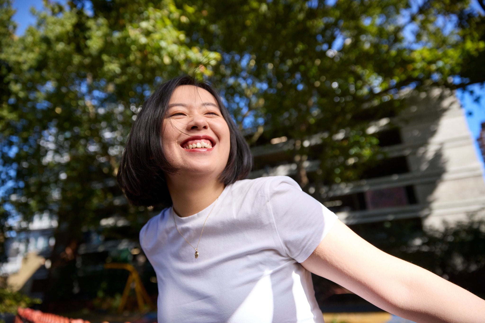 Person smiling outdoors with trees behind