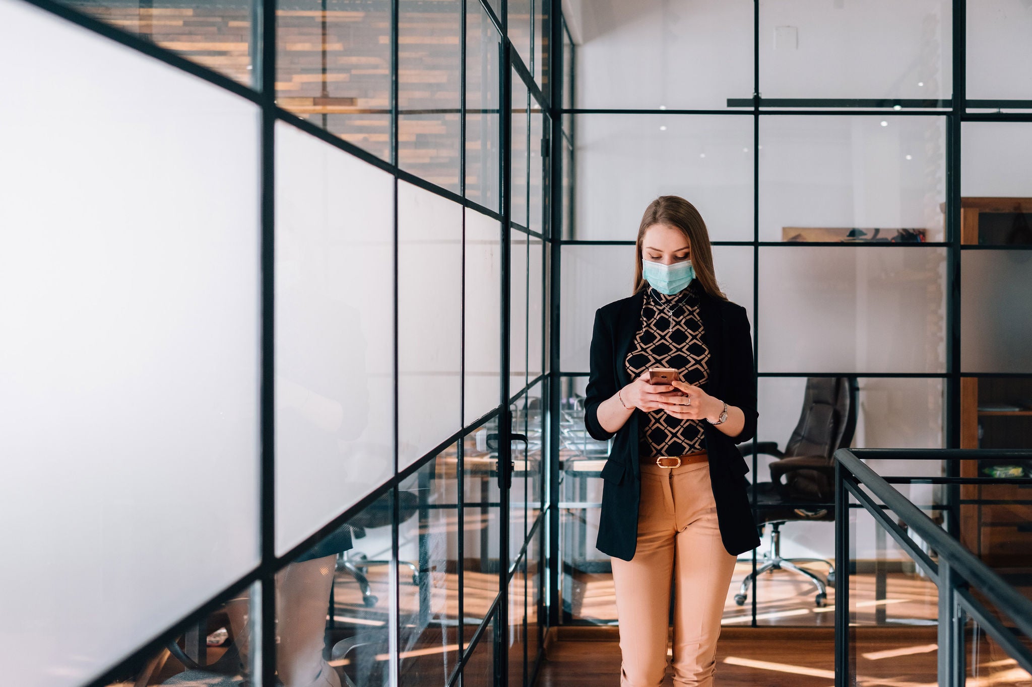 Businesswoman on mobile phone wearing mask in the office