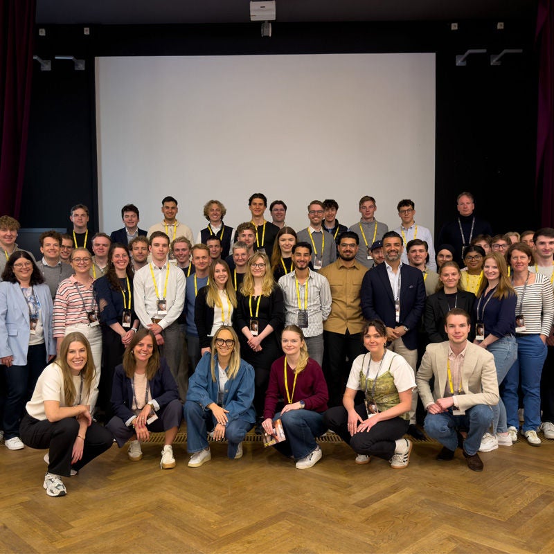Große Gruppe von Teilnehmenden vor einer Präsentationsleinwand bei einer Veranstaltung.