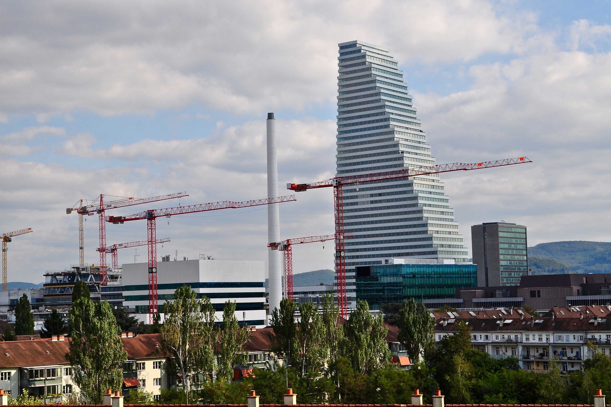 Hausdächer in Basel mit Baukranen, Hochhäuser und Roche Tower
