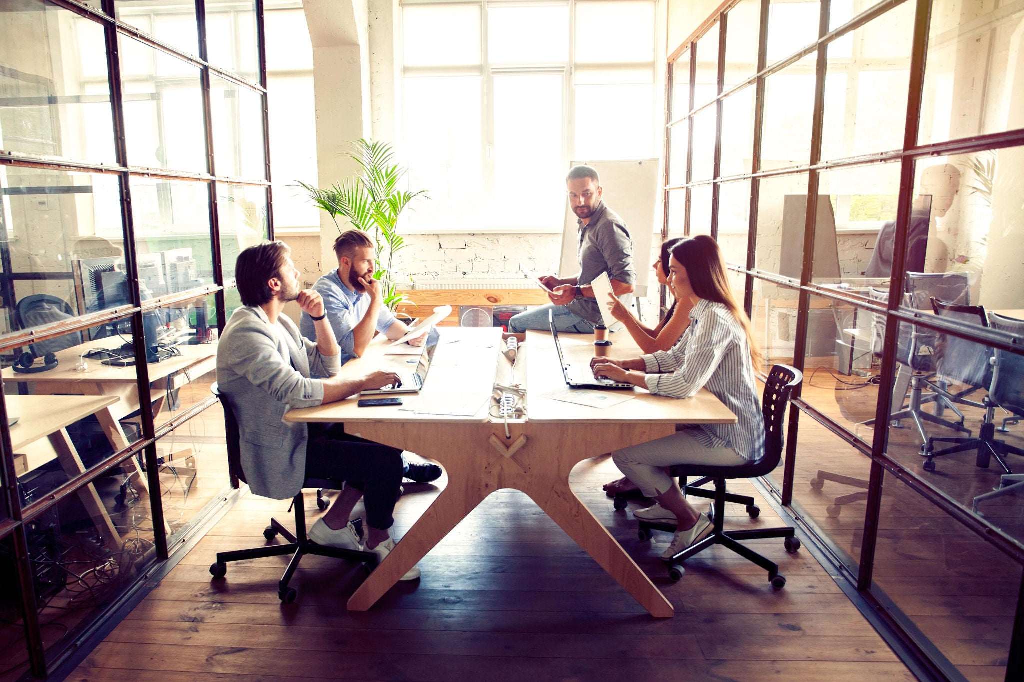 Man near whiteboard and pointing on the chart while his coworkers listening