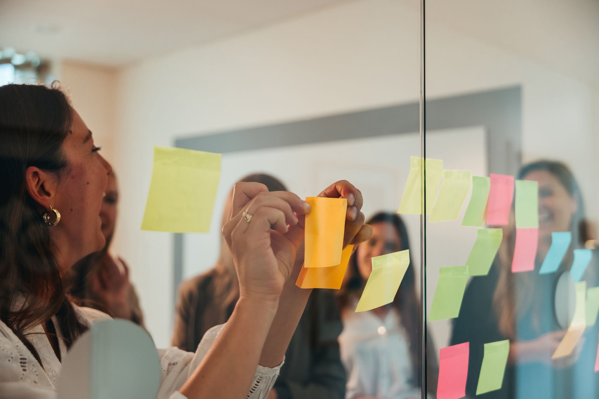 Employees reviewing notes on glass board during team collaboration