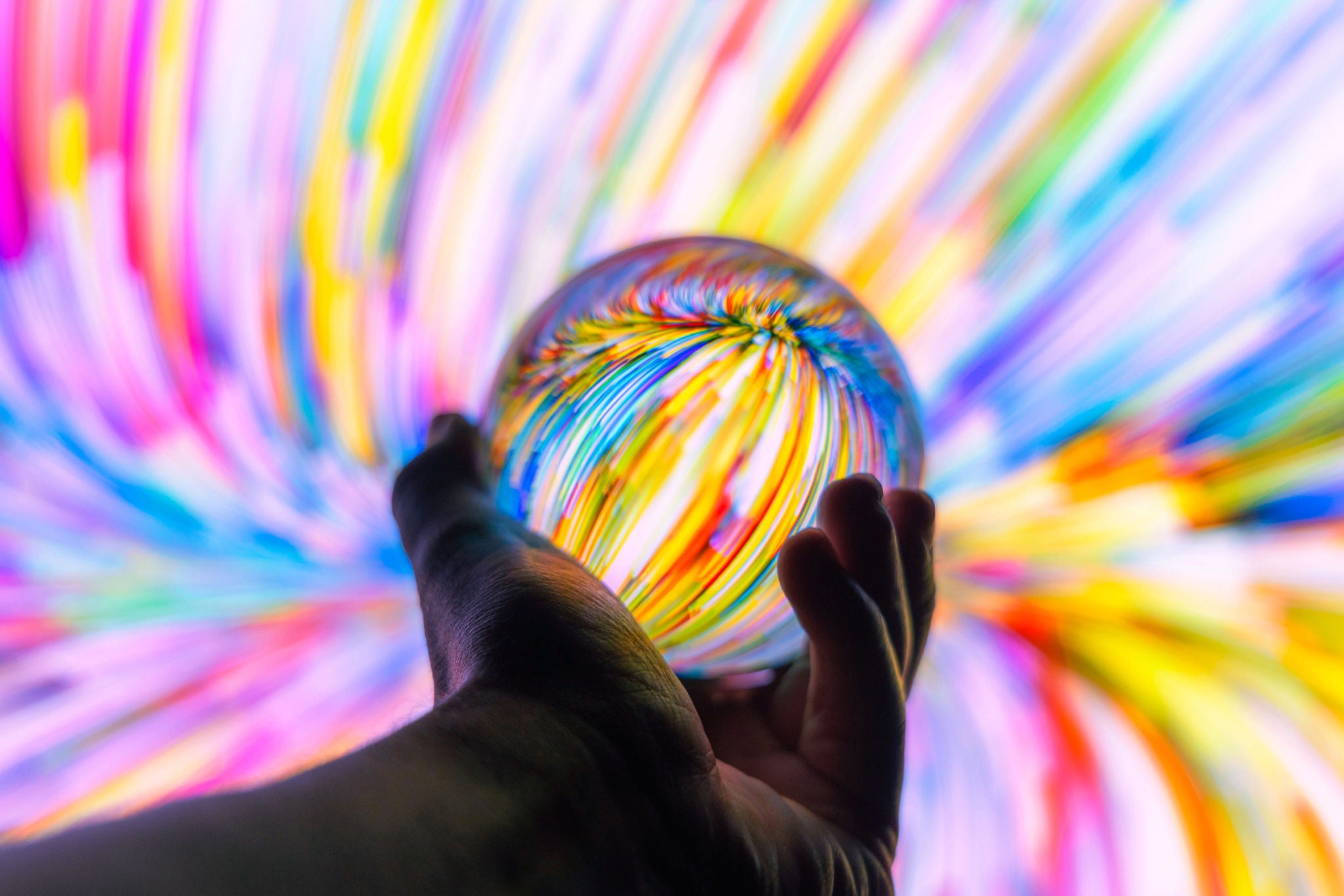 A mesmerising glass orb illuminated by vivid streaks of light in dazzling colours.