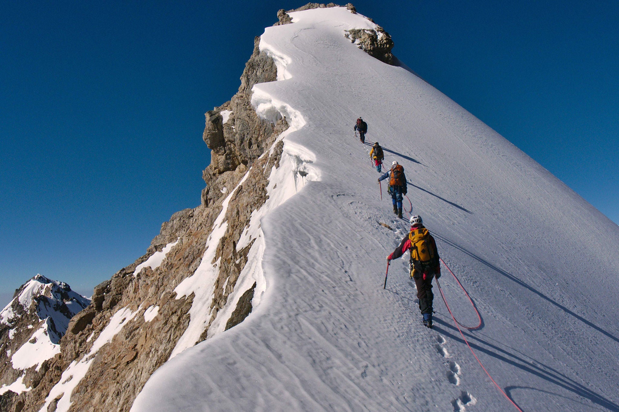 A Team of Mountaineers Climbing a mountain with safety ropes working as a team