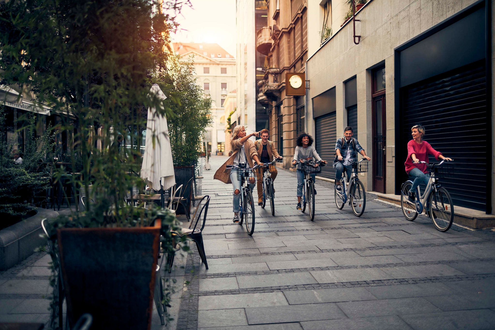 Friends Riding Bicycles In A City. Cycling in pedestrian zone and smiling.