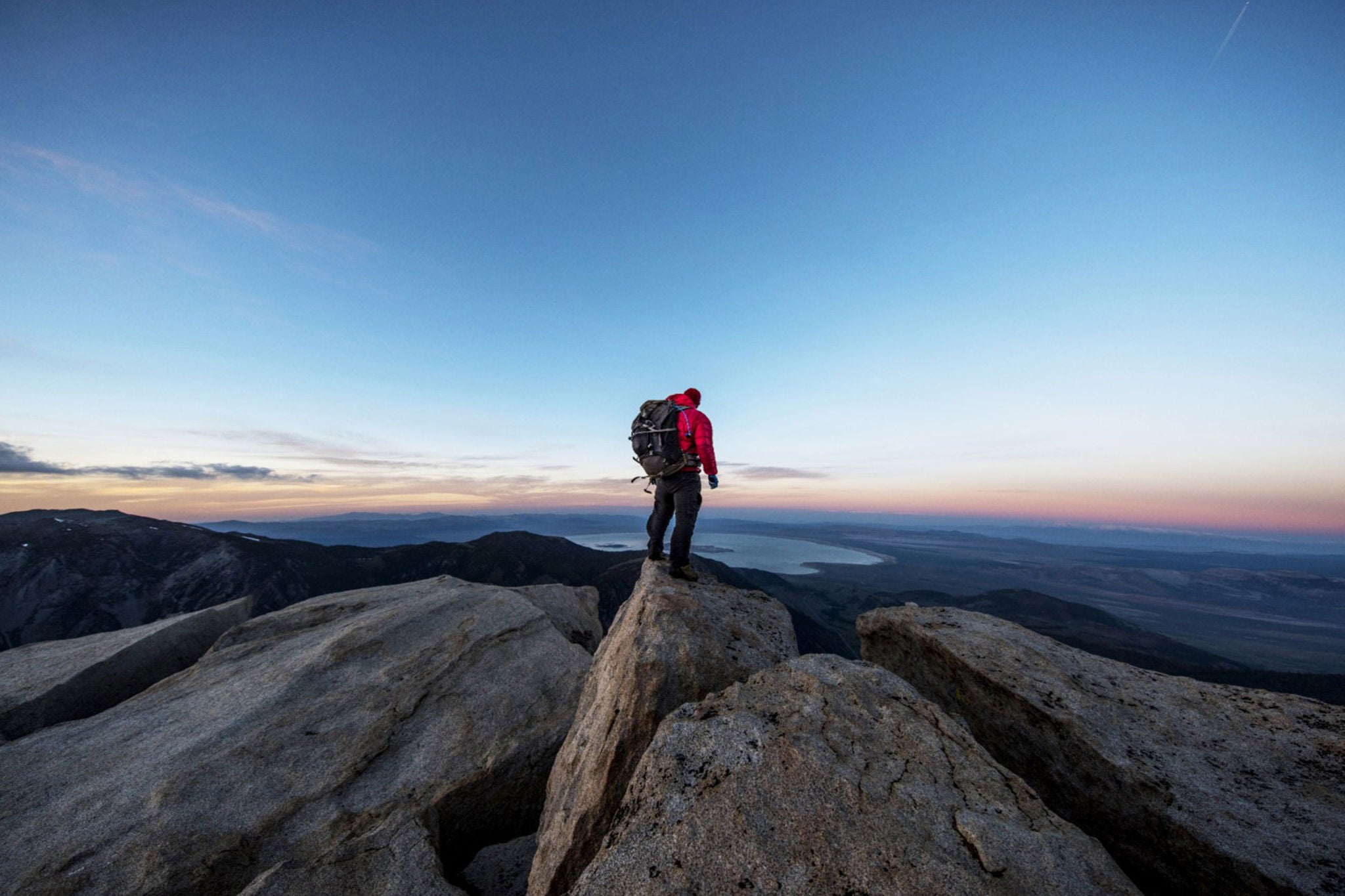 Strong mountain climber on the summit of a peak watching sunset