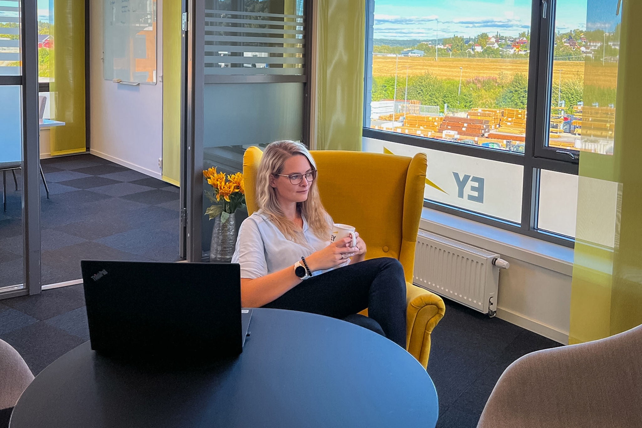 Kristina Sakariassen fra EY Skye ser ut over kontorlandskapet mens hun sitter i en stol på EY Skye-kontorene.