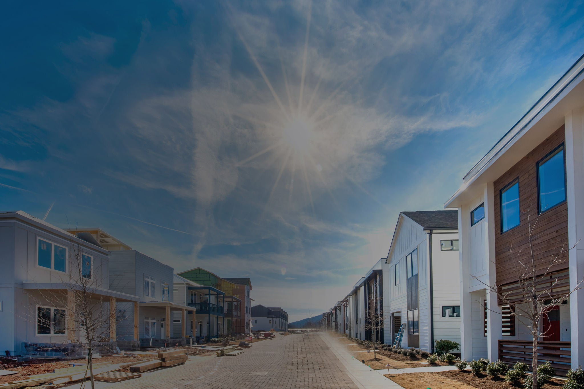 New housing development featuring modern homes, bright sunshine, and a well-planned neighborhood street.