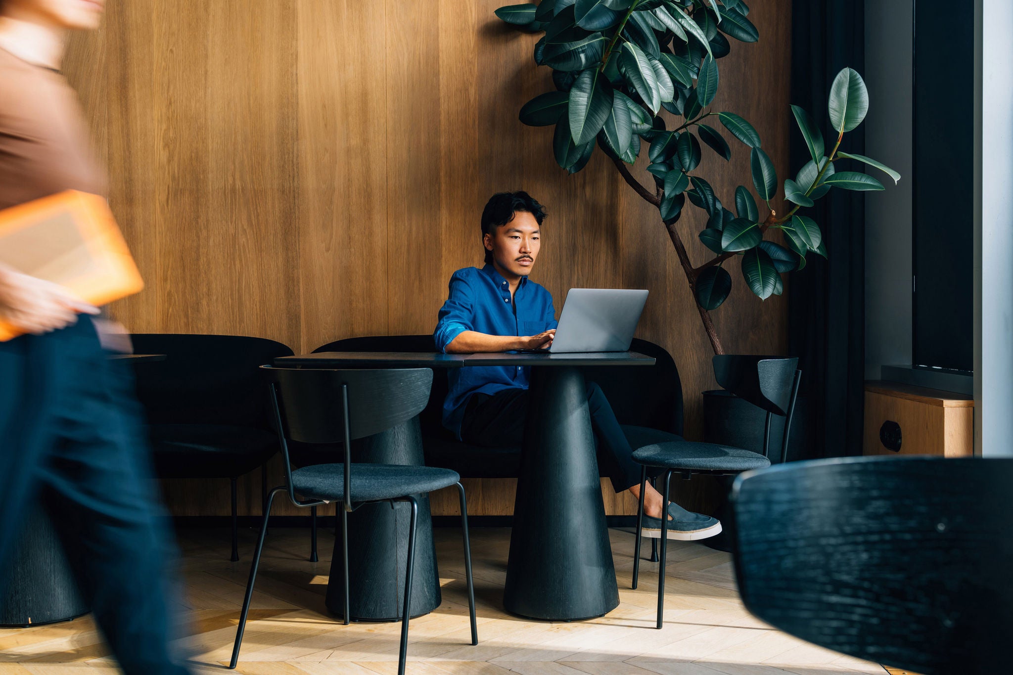 Focused Asian businessman in a blue shirt working on a laptop.