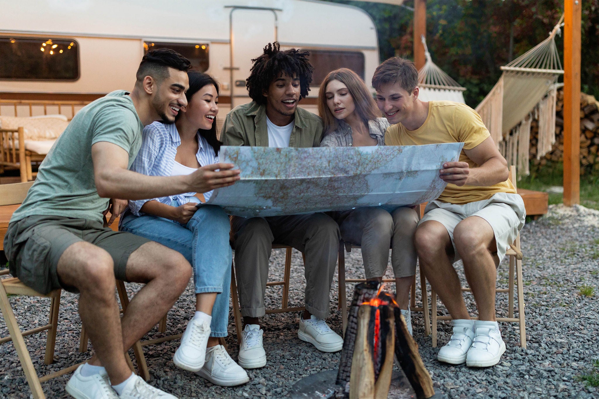Happy multiracial young people sitting near campfire
