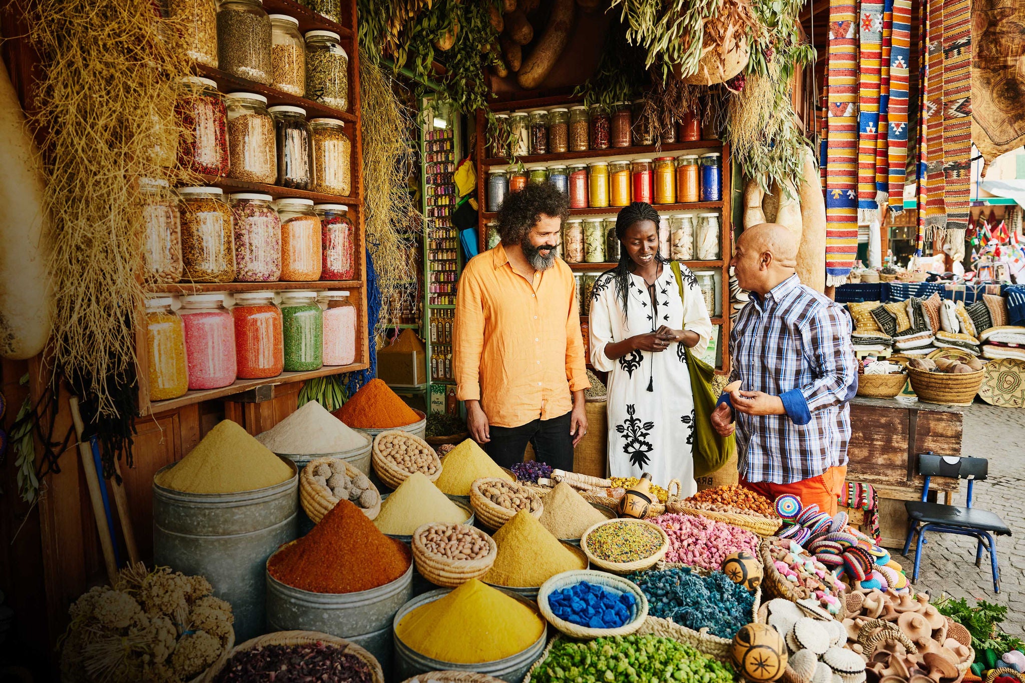 Couple talking to shop owner while shopping in spice shop in the souks of Marrakech during vacation