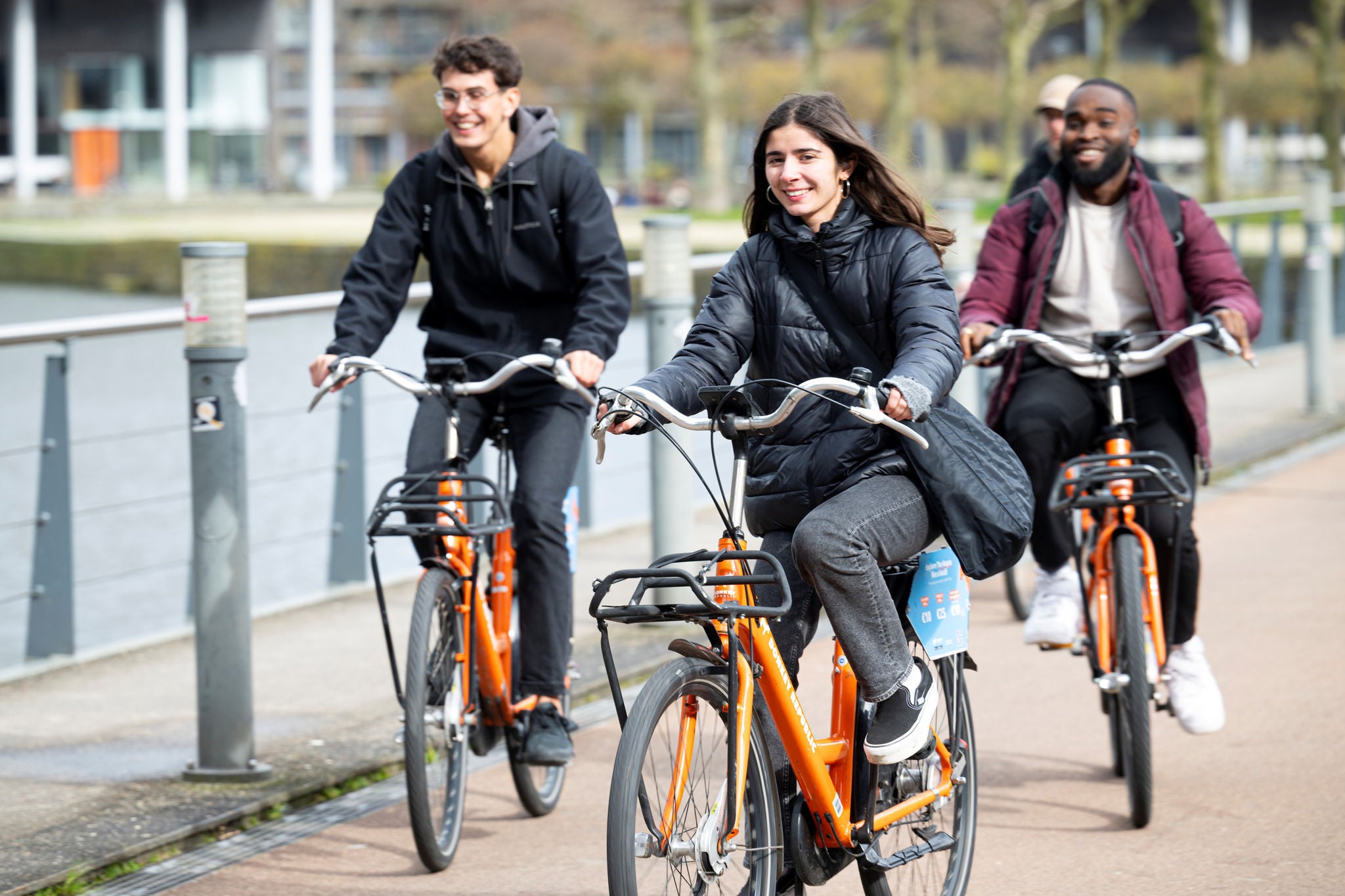 Groupe faisant du vélo orange sur un chemin urbain au bord de l’eau